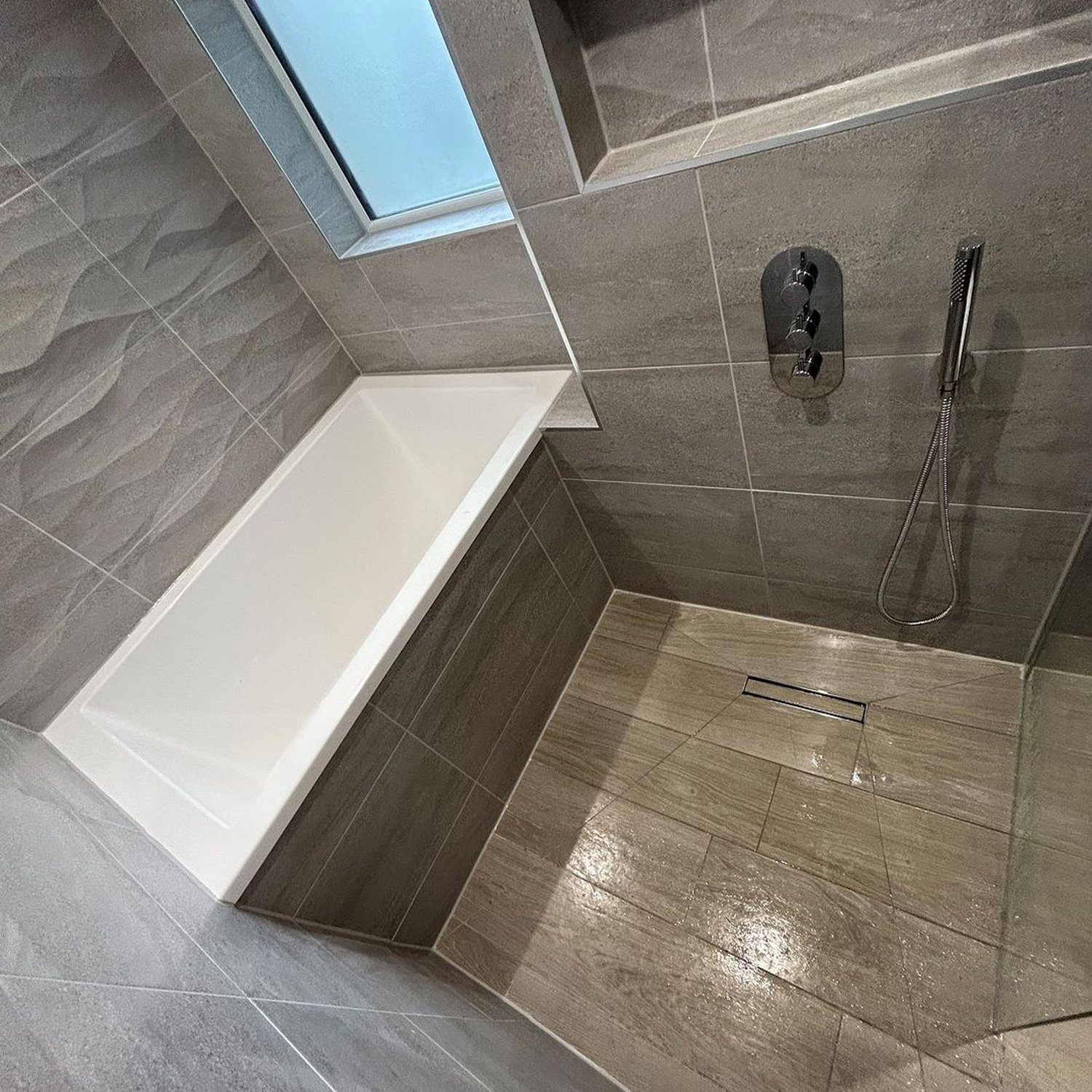 A modernly designed bathroom featuring a skylight, tiled walls, and a walk-in shower with a seamless glass screen.