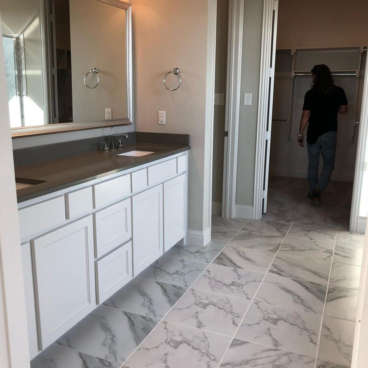 A modern and sleek bathroom featuring marble-like tiles and a clean white vanity