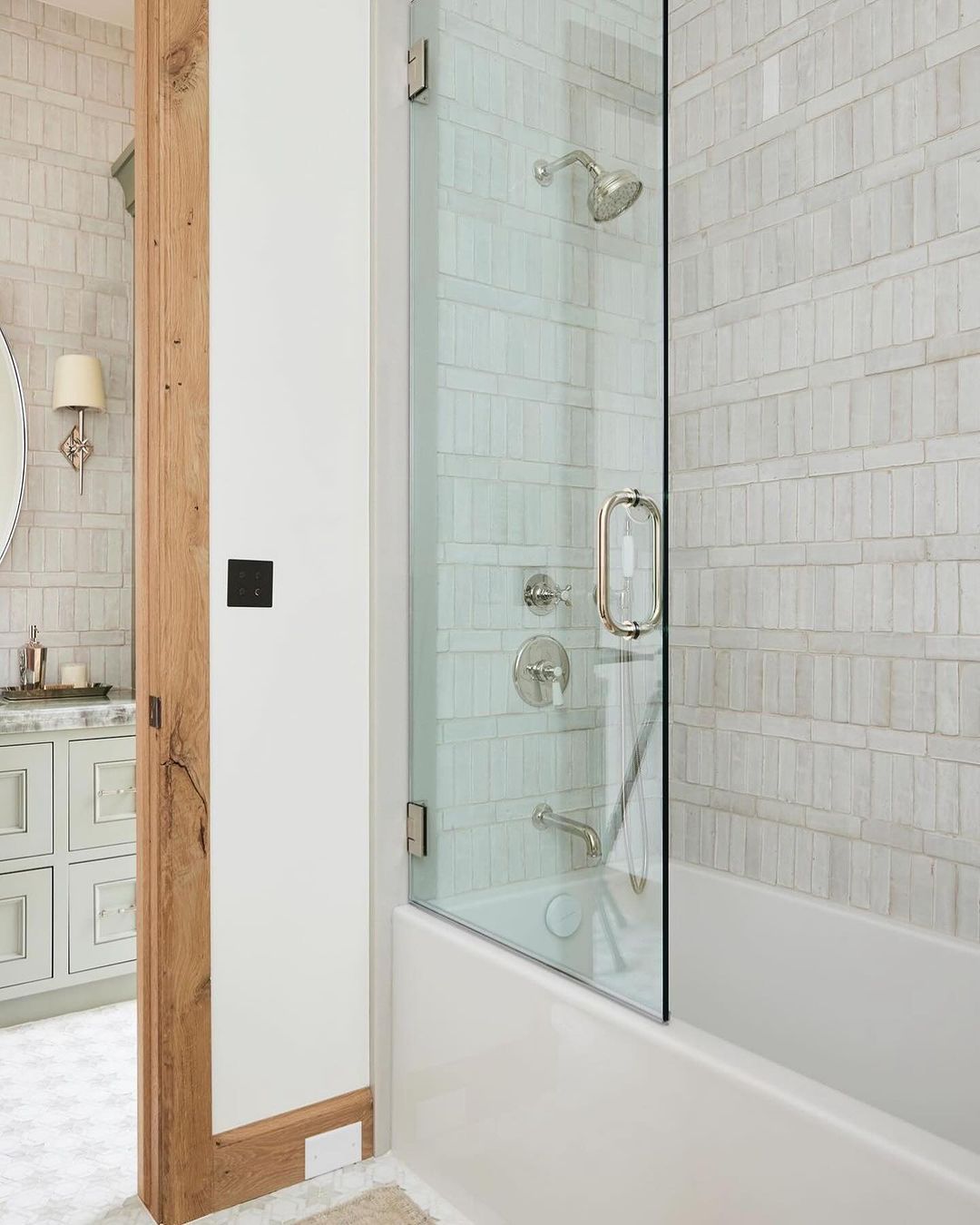 A modern bathroom with a glass shower enclosure, subway-tiled walls, and wooden accents