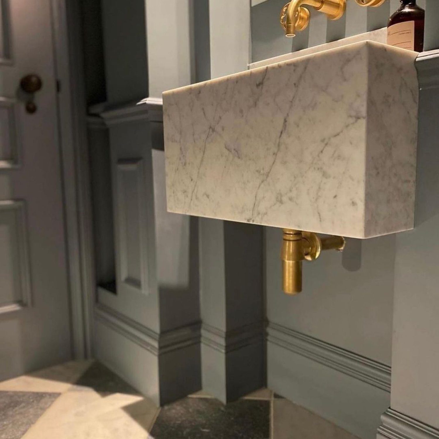 A minimalist bathroom featuring a marble basin with an elegant gold faucet