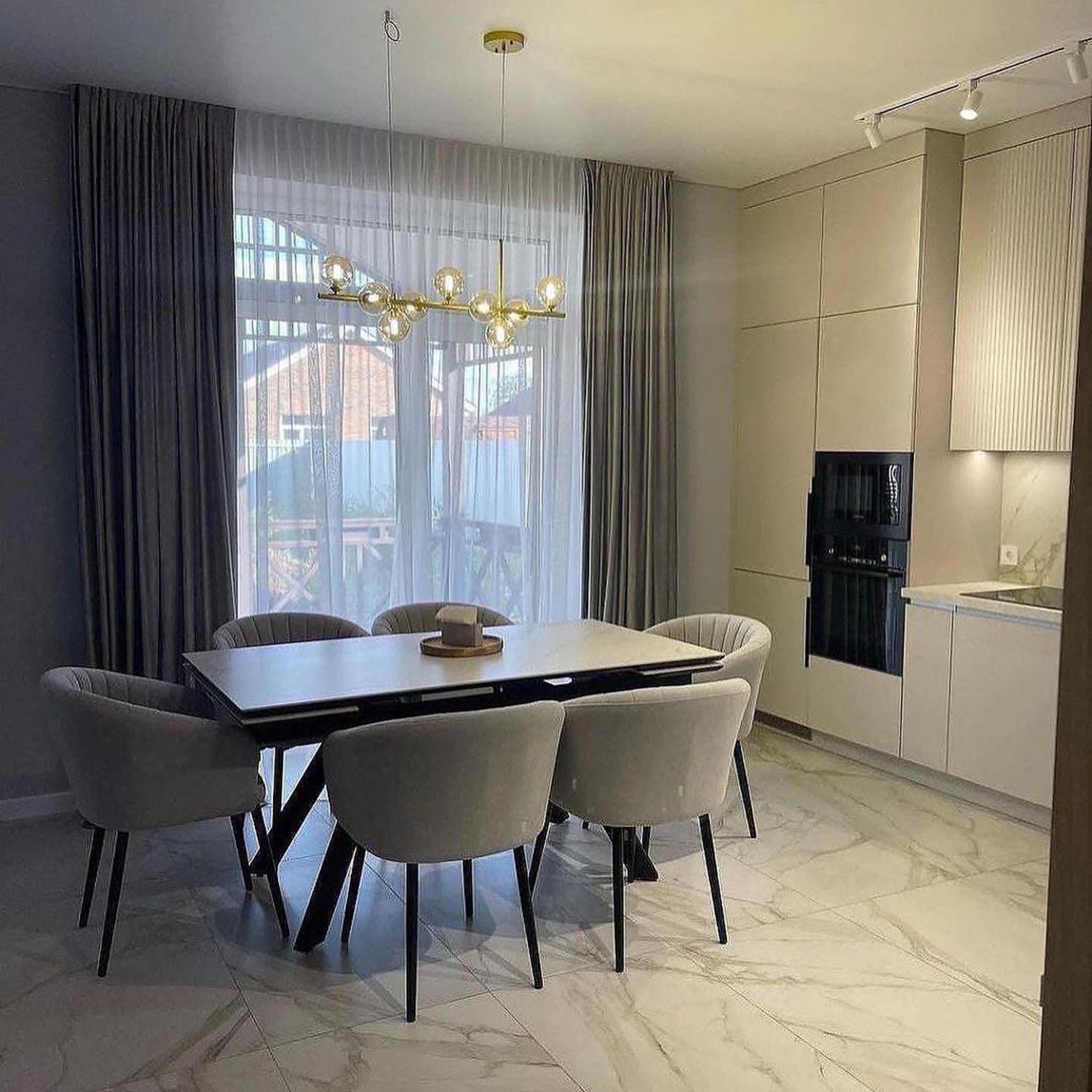 Elegant contemporary dining and kitchen area with a blend of natural light and stylish lighting fixtures