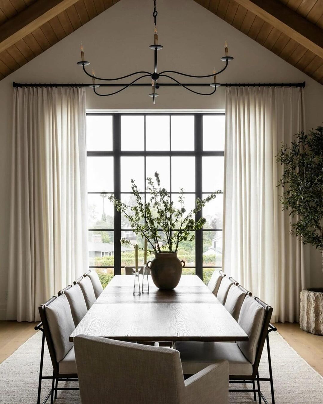 A modern and minimalist dining room featuring a large wooden table surrounded by stylish chairs