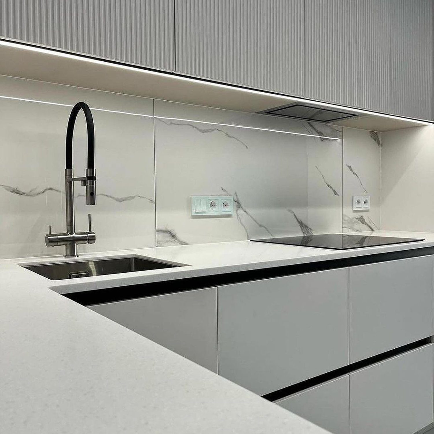 Sleek and modern kitchen design featuring a monochromatic color scheme and marble backsplash