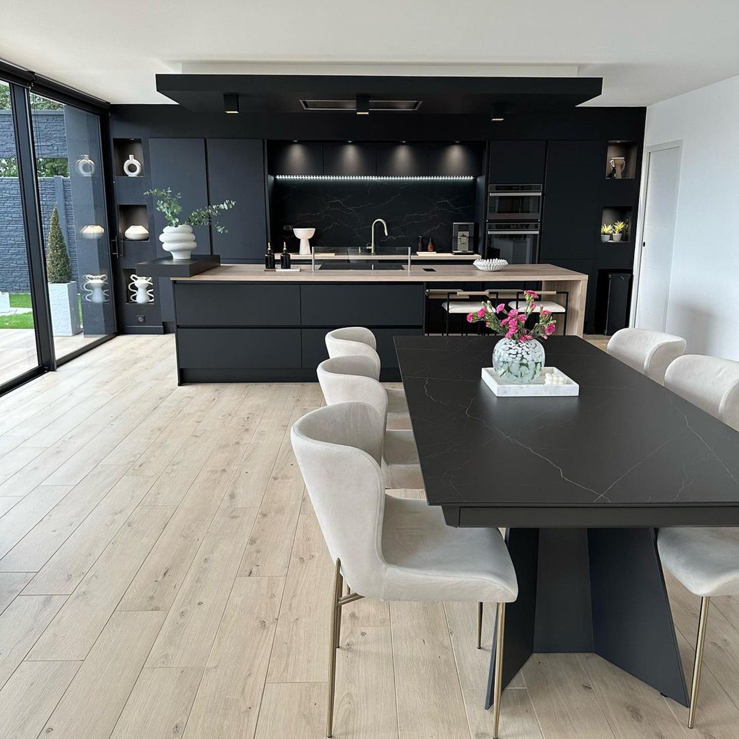 Modern and sleek kitchen with contrasting dark cabinetry and light wood floors