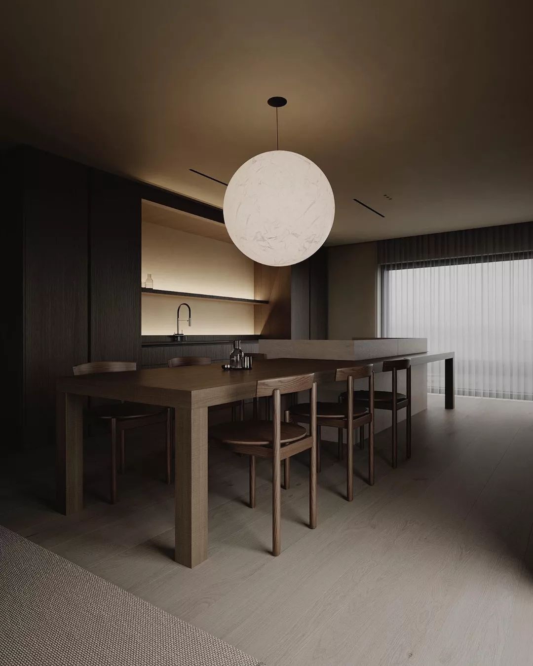 A modern kitchen with a minimalistic design featuring a bold spherical pendant light over a matching wooden dining table and chairs