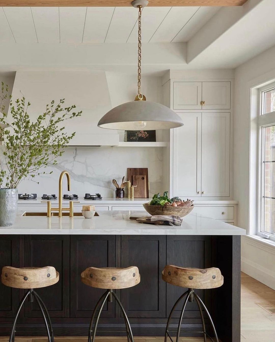 A modern and sleek kitchen featuring a contrasting color palette with dark wood island base and white marble countertop.