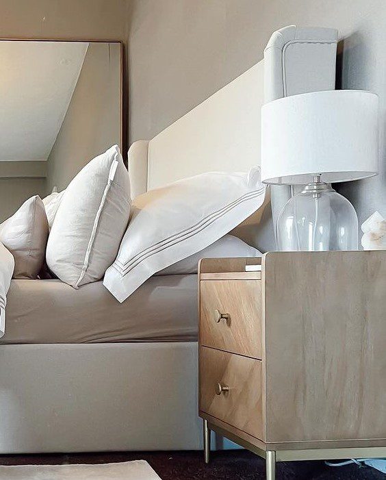 A neatly arranged living space with a plush beige sofa, complemented by a wooden nightstand and a classic white lamp.