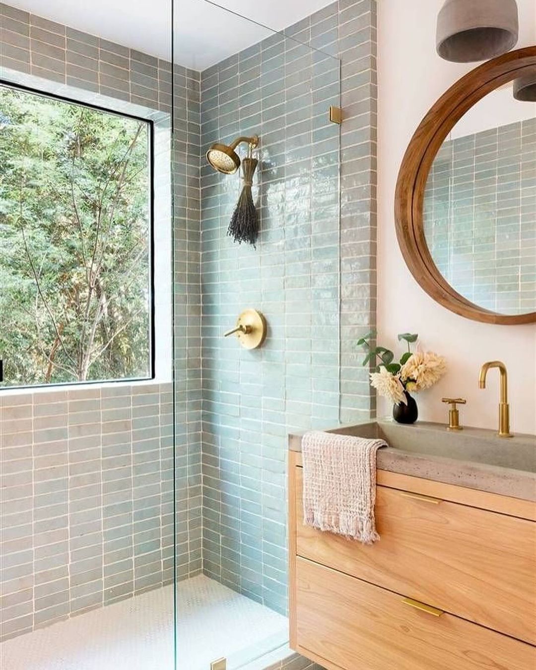 A contemporary bathroom featuring a serene palette of soft blue tiles and a natural wood vanity.