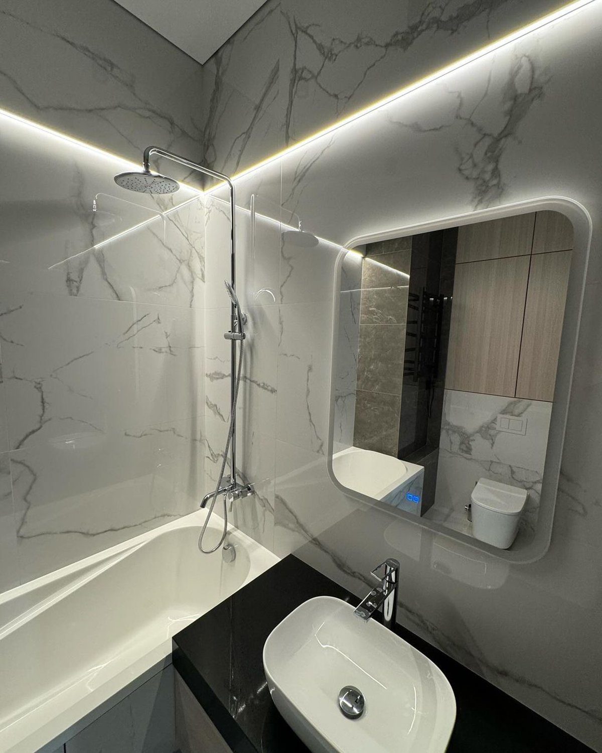 Modern bathroom with marble patterned walls, a glass-enclosed bathtub, sleek fixtures, and contemporary lighting