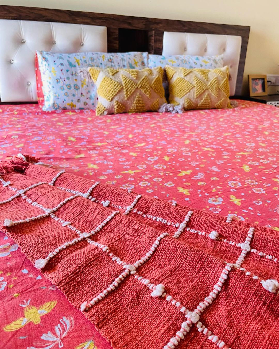 A beautifully made bed with a colorful patterned bedspread and cozy pillows