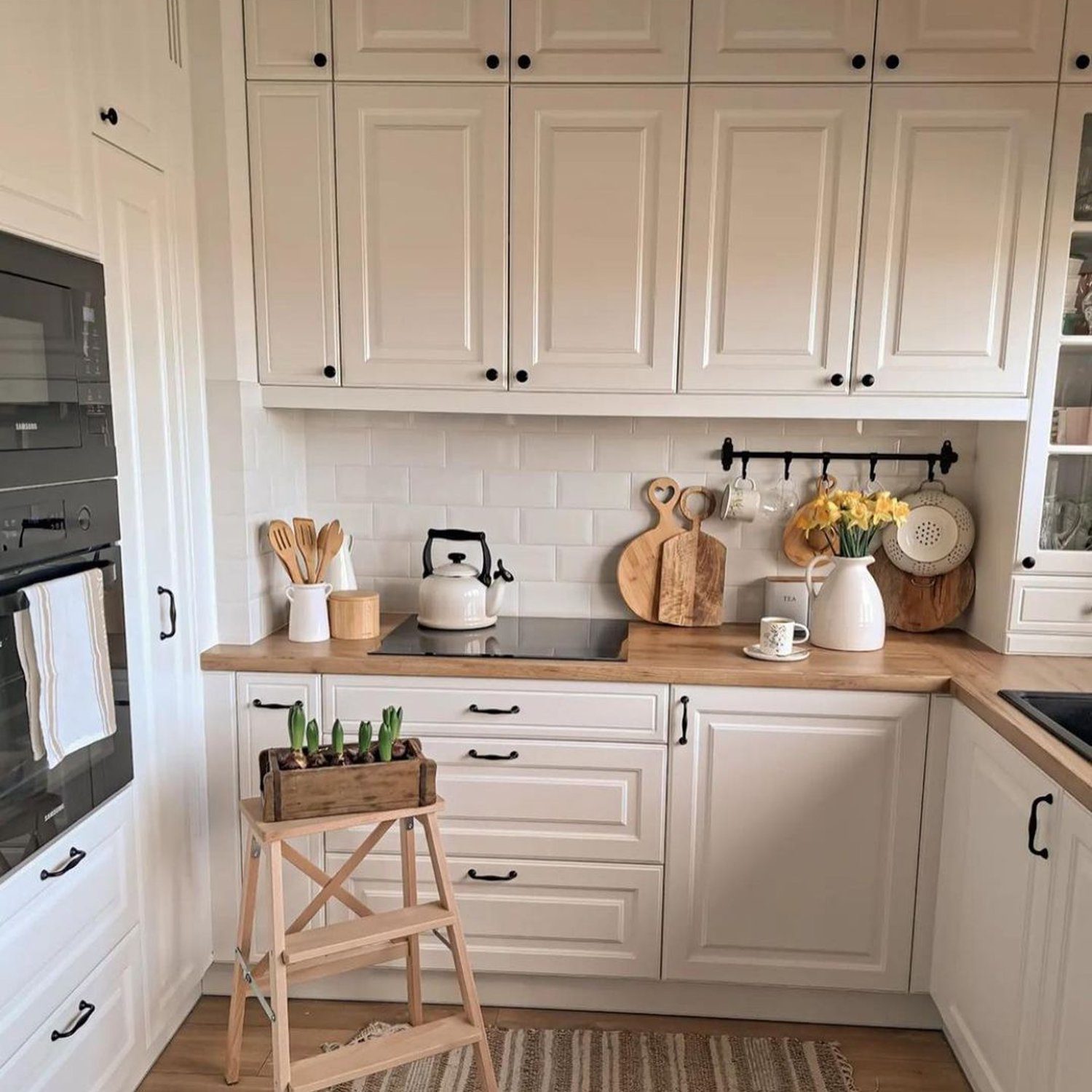 A neatly organized kitchen with white cabinetry, wooden countertops, and modern appliances