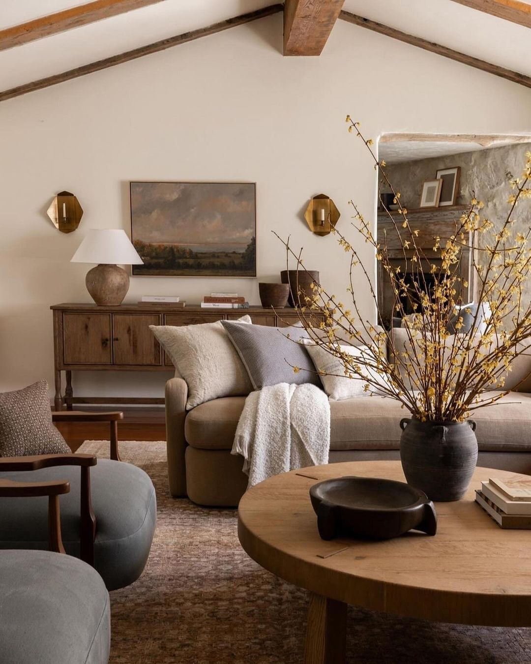 A cozy and welcoming living room space with exposed wooden beams and a warm color palette