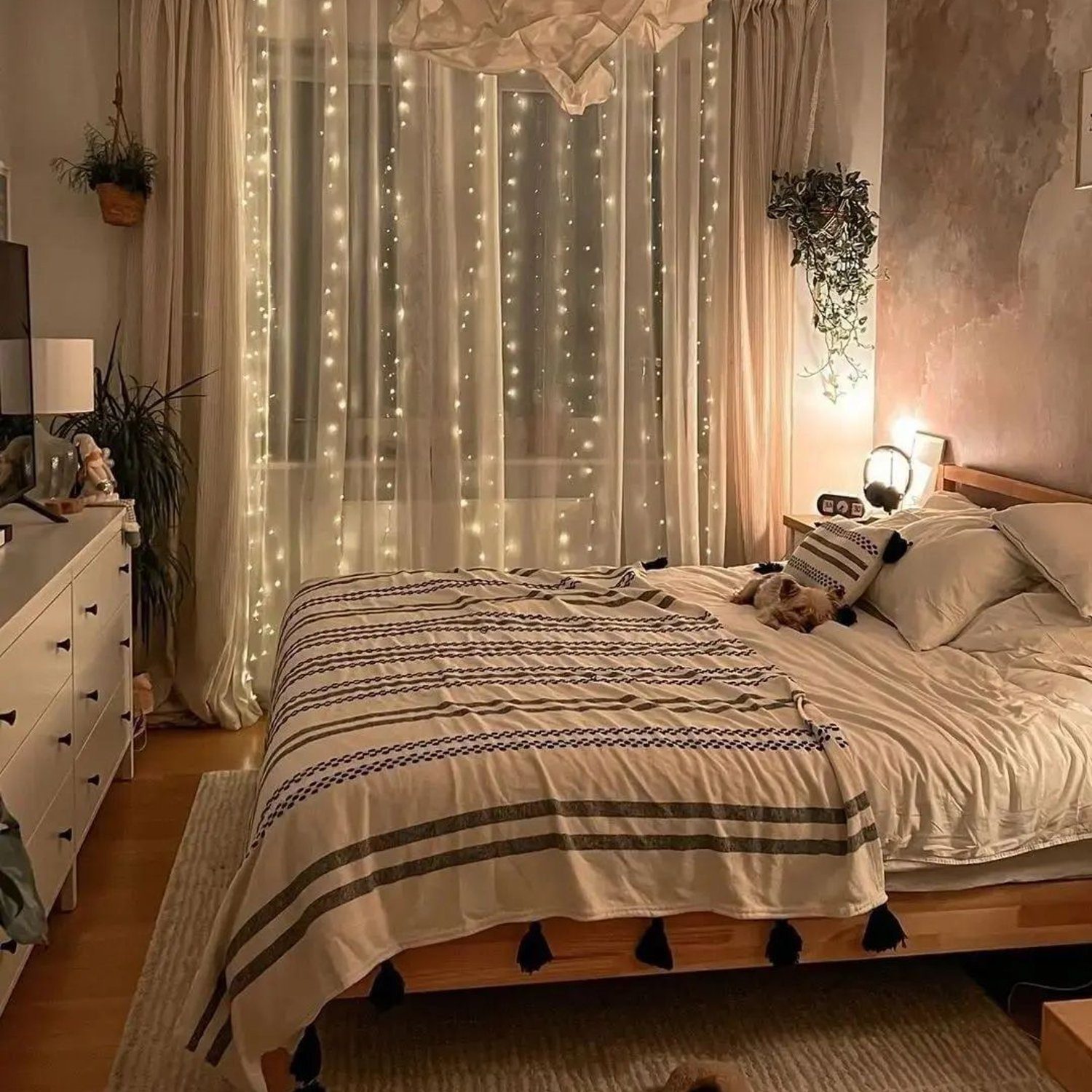 Cozy bedroom with twinkling fairy lights behind sheer curtains