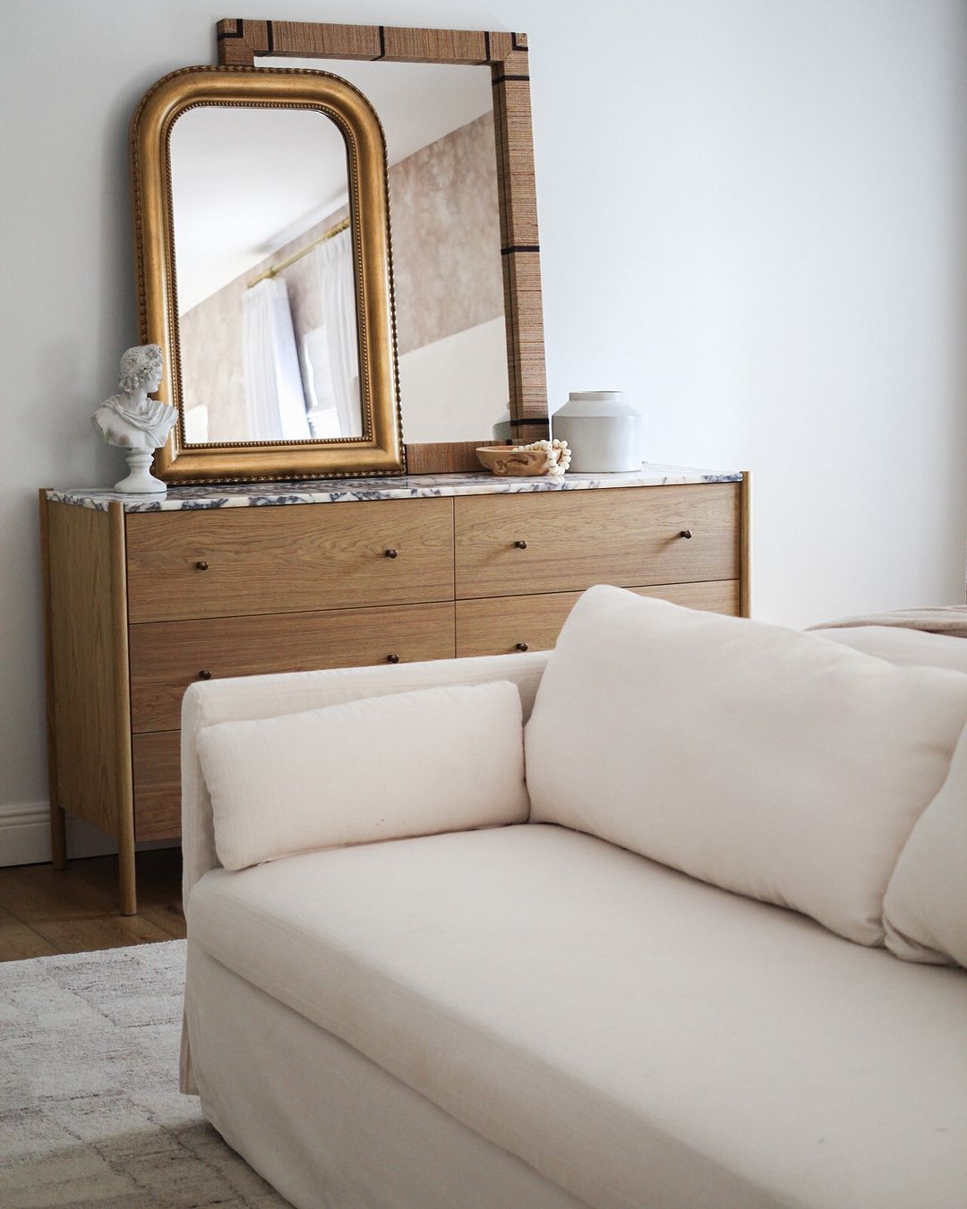 A cozy bedroom corner with a plush sofa and vintage-style dresser