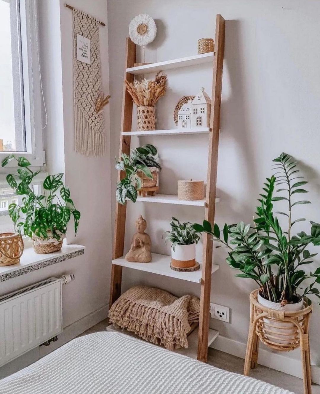 A cozy bedroom corner with a leaning ladder shelf adorned with houseplants and woven decorations