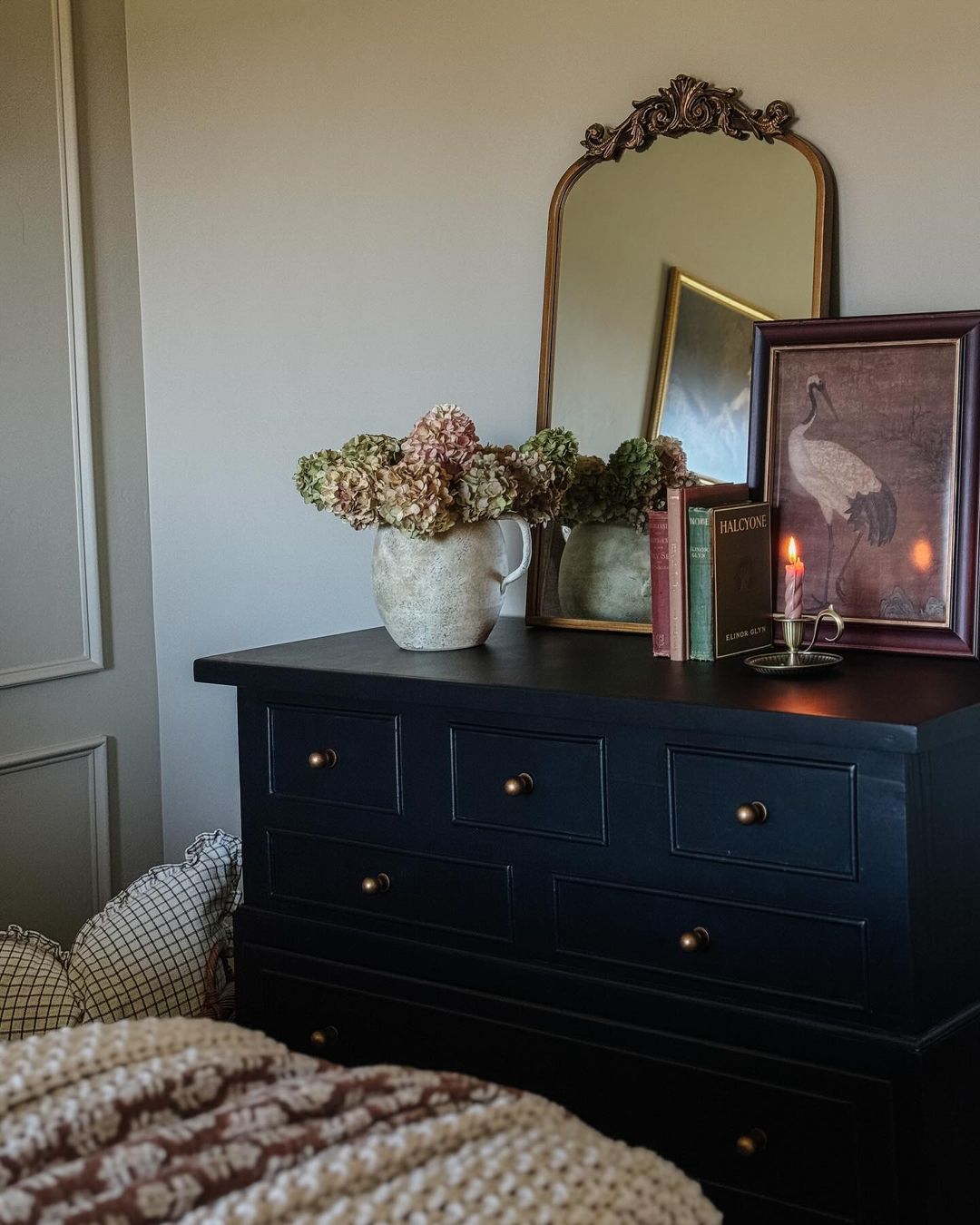 A tastefully decorated bedroom corner featuring a black dresser with brass handles