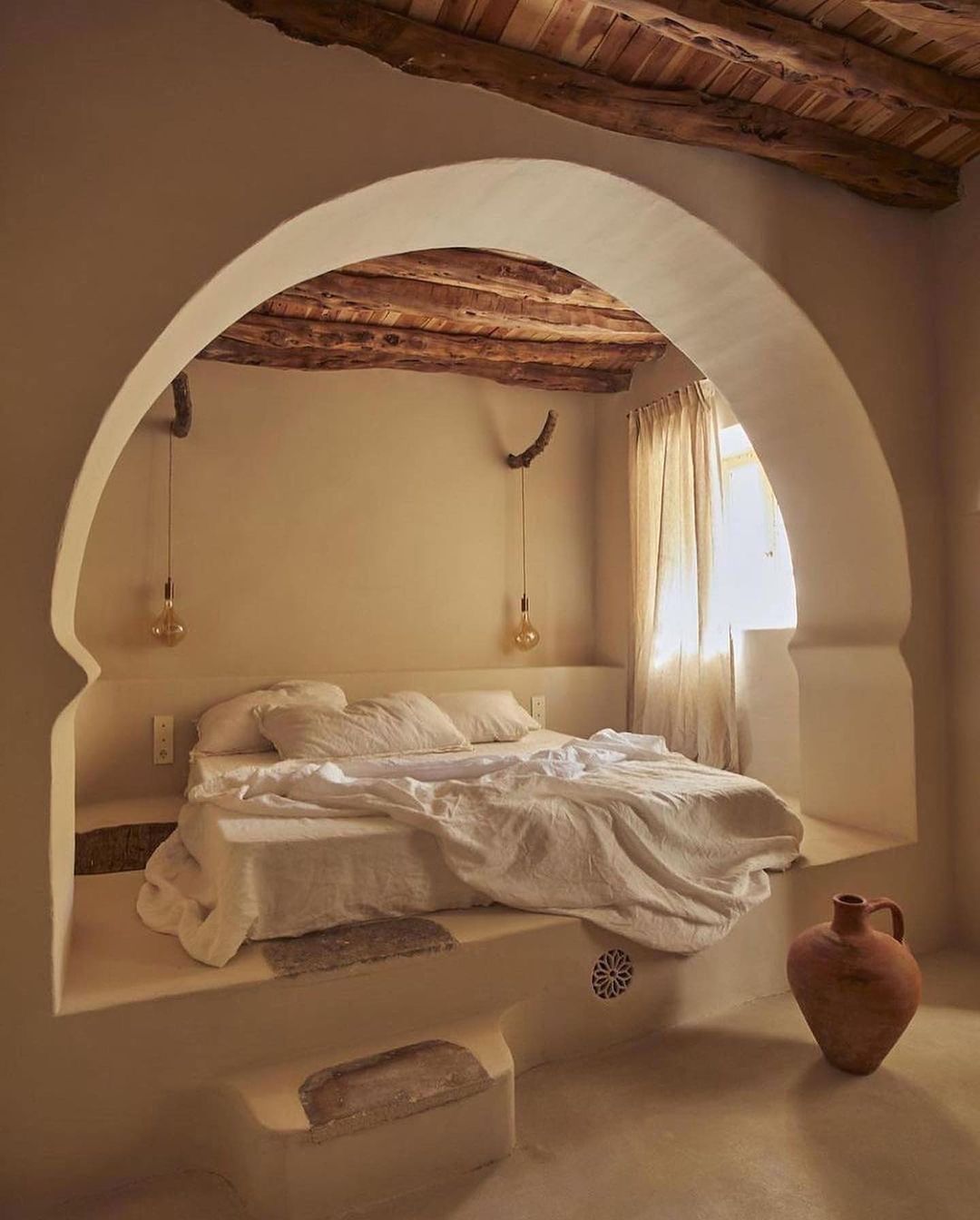 A cozy bedroom nook featuring a raised platform bed with earth-toned bedding