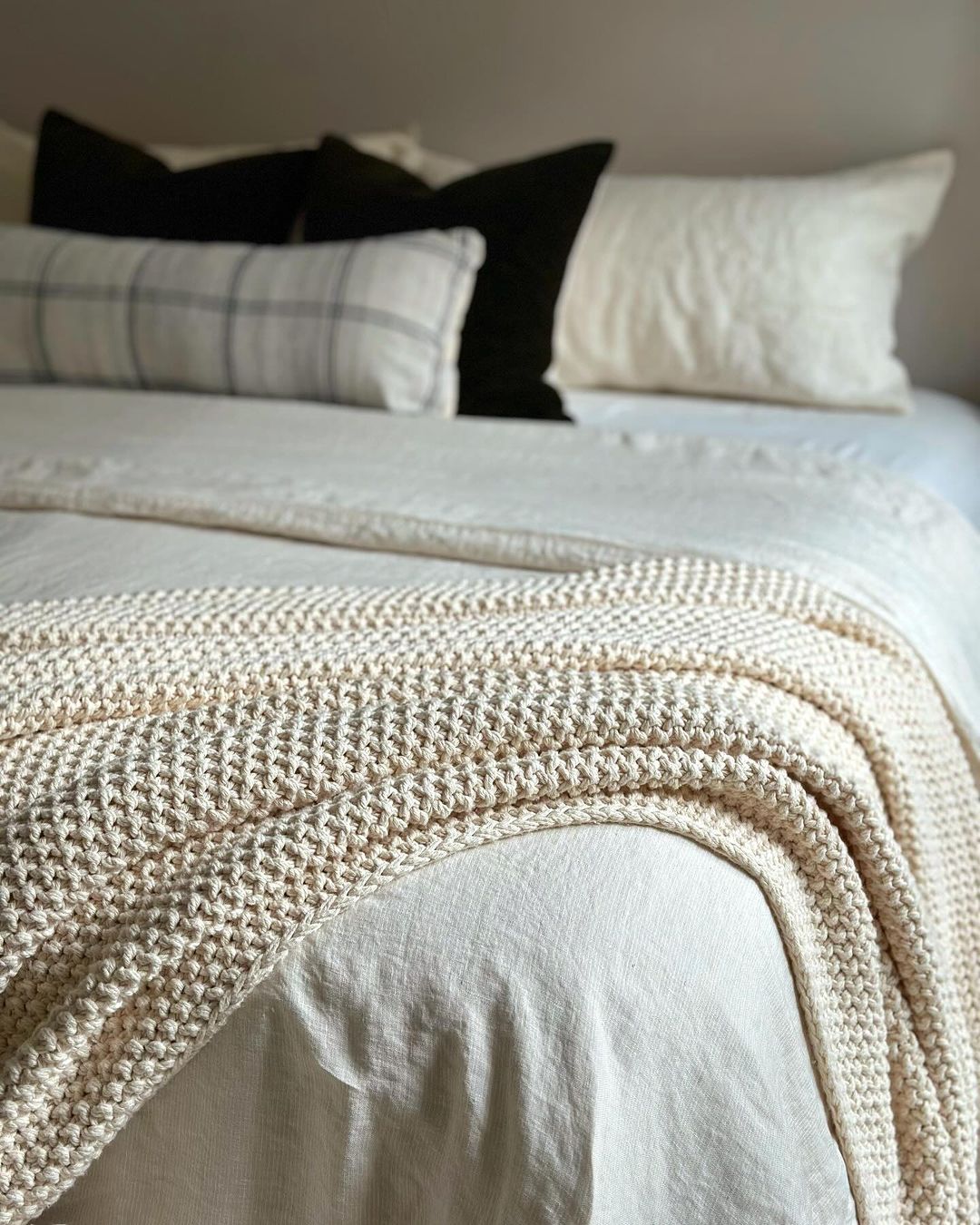 A neatly made bed with a textured throw blanket