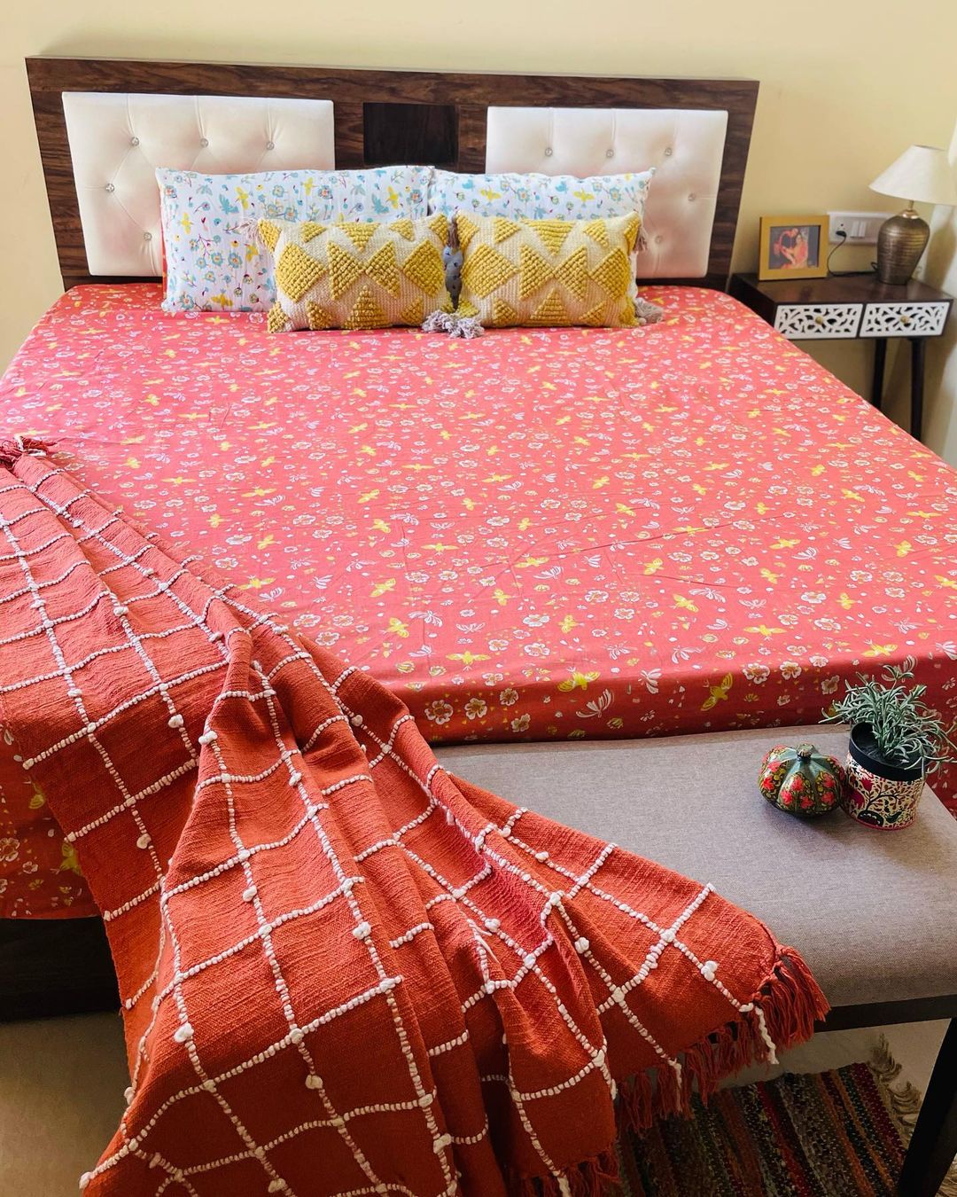 A well-arranged bedroom with a vibrantly patterned bedspread and a cozy red throw