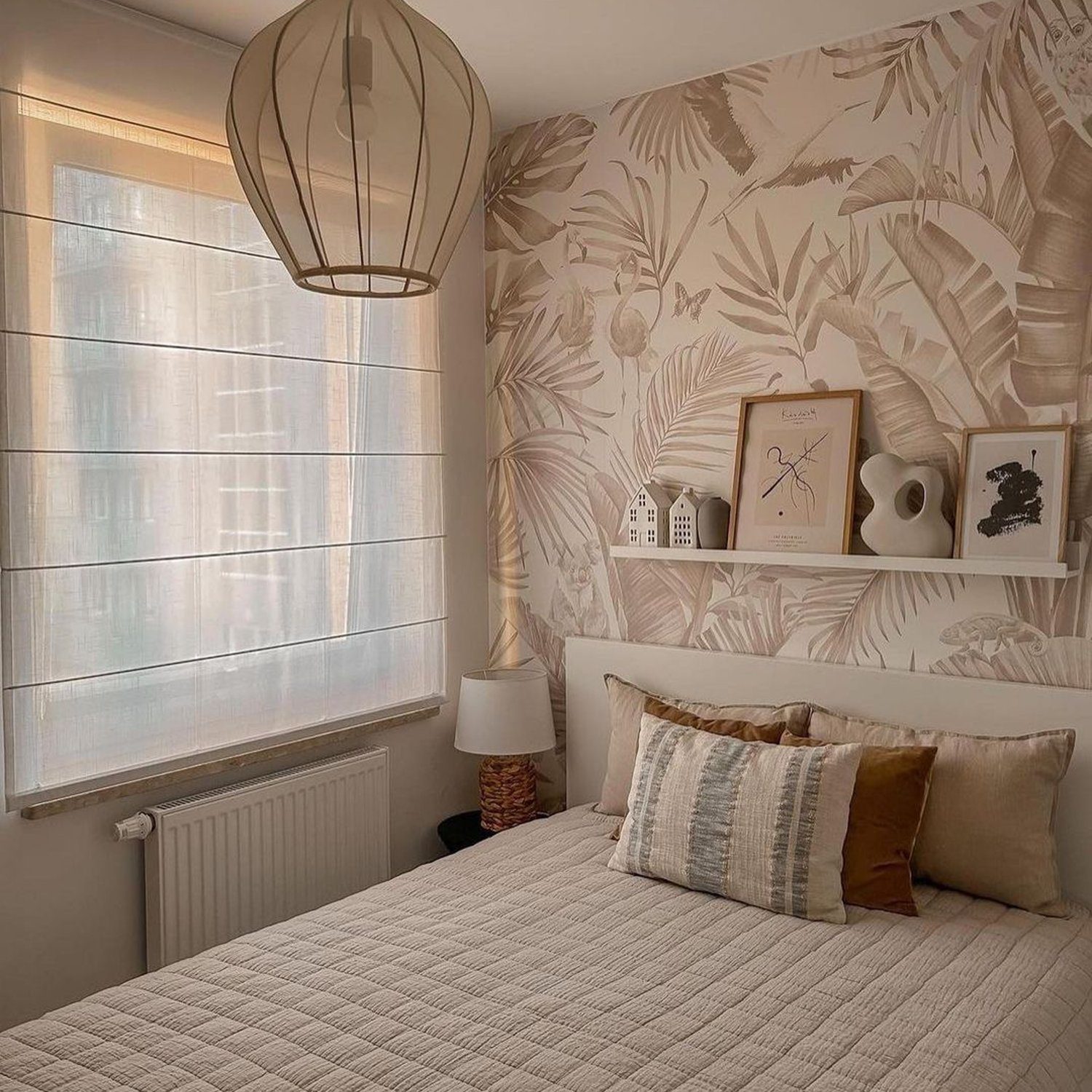 A cozy bedroom featuring a botanical-themed wallpaper and neutral-toned bedding