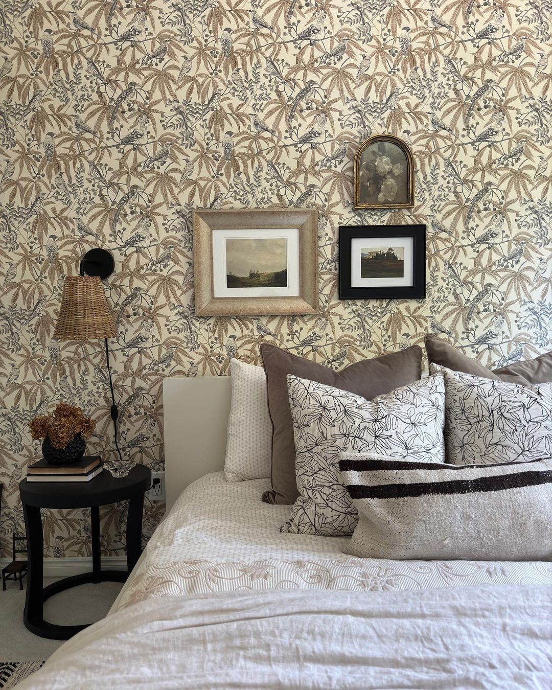 Cozy bedroom with botanical wallpaper and a mix of textured cushions