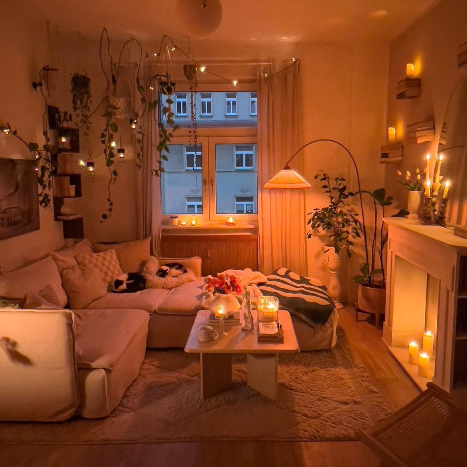 A cosy living room featuring warm candlelight, plush seating, and abundant plant life