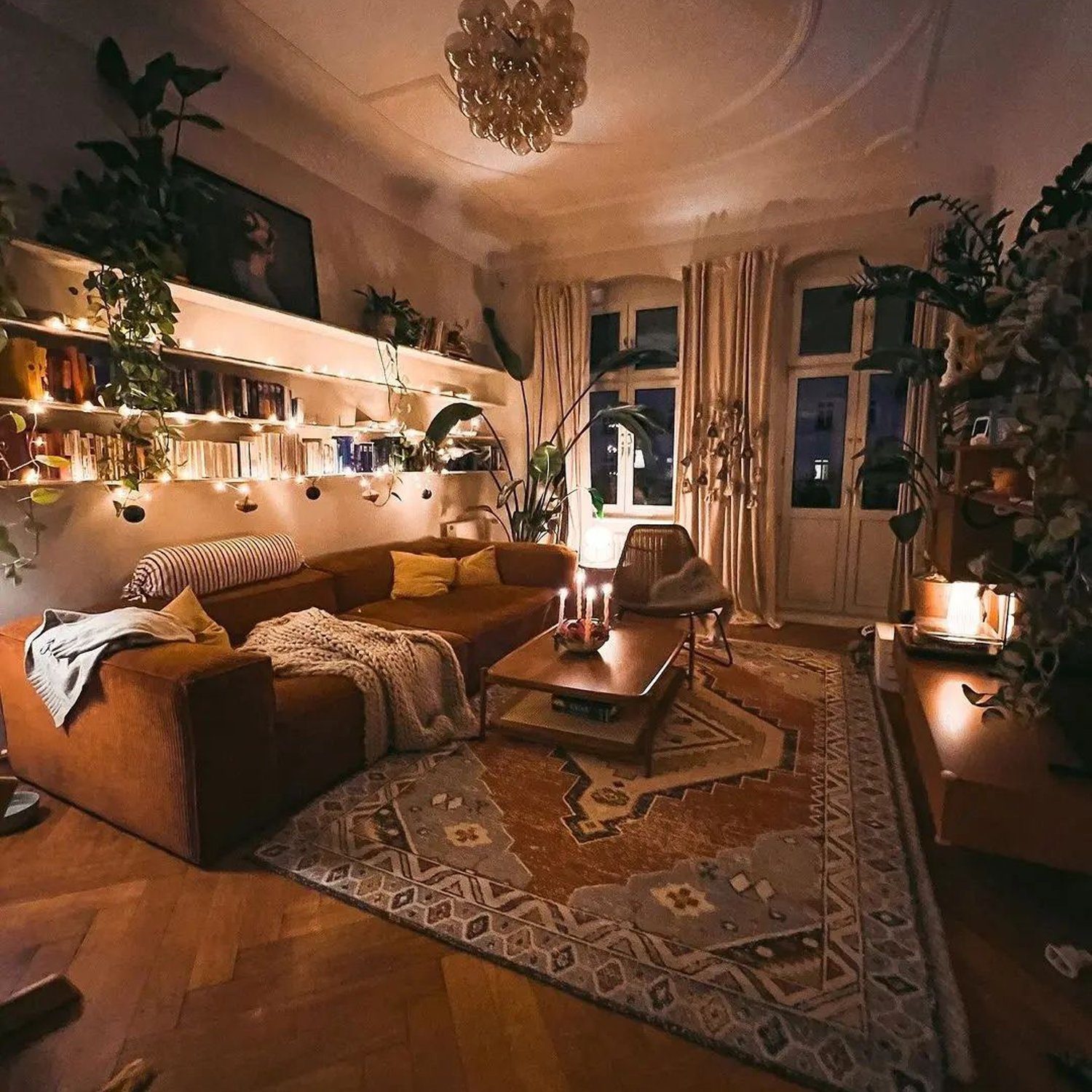 A cozy living room boasting a warm ambiance with dim lighting, comfortable seating and an array of indoor plants.