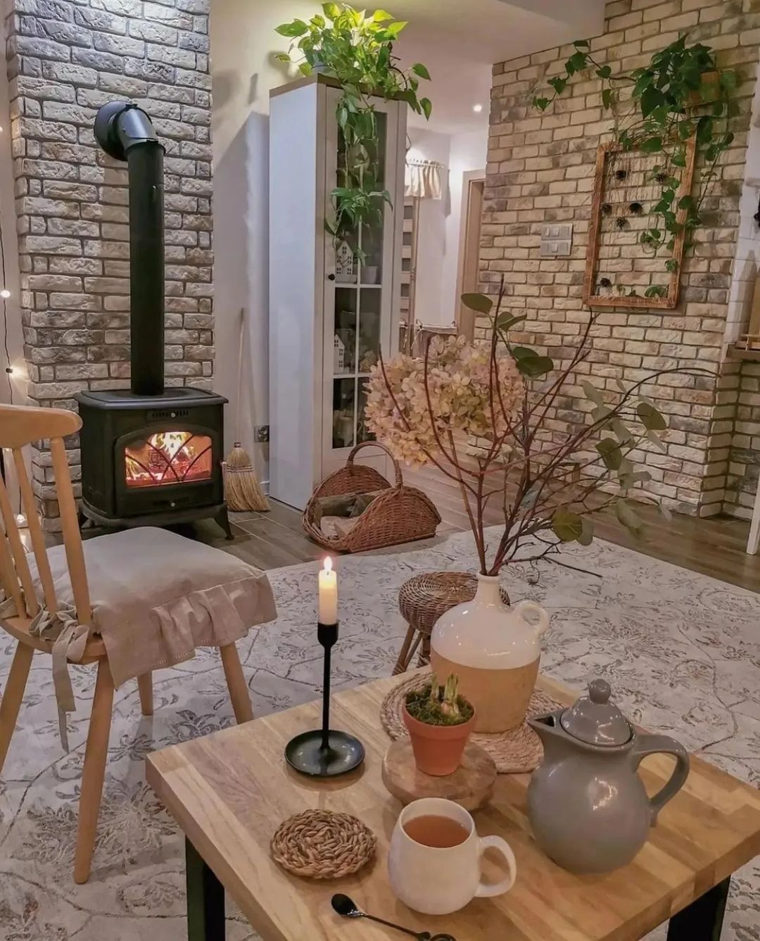 Cozy interior with a wood-burning stove, brick details, and a warm tea setting.