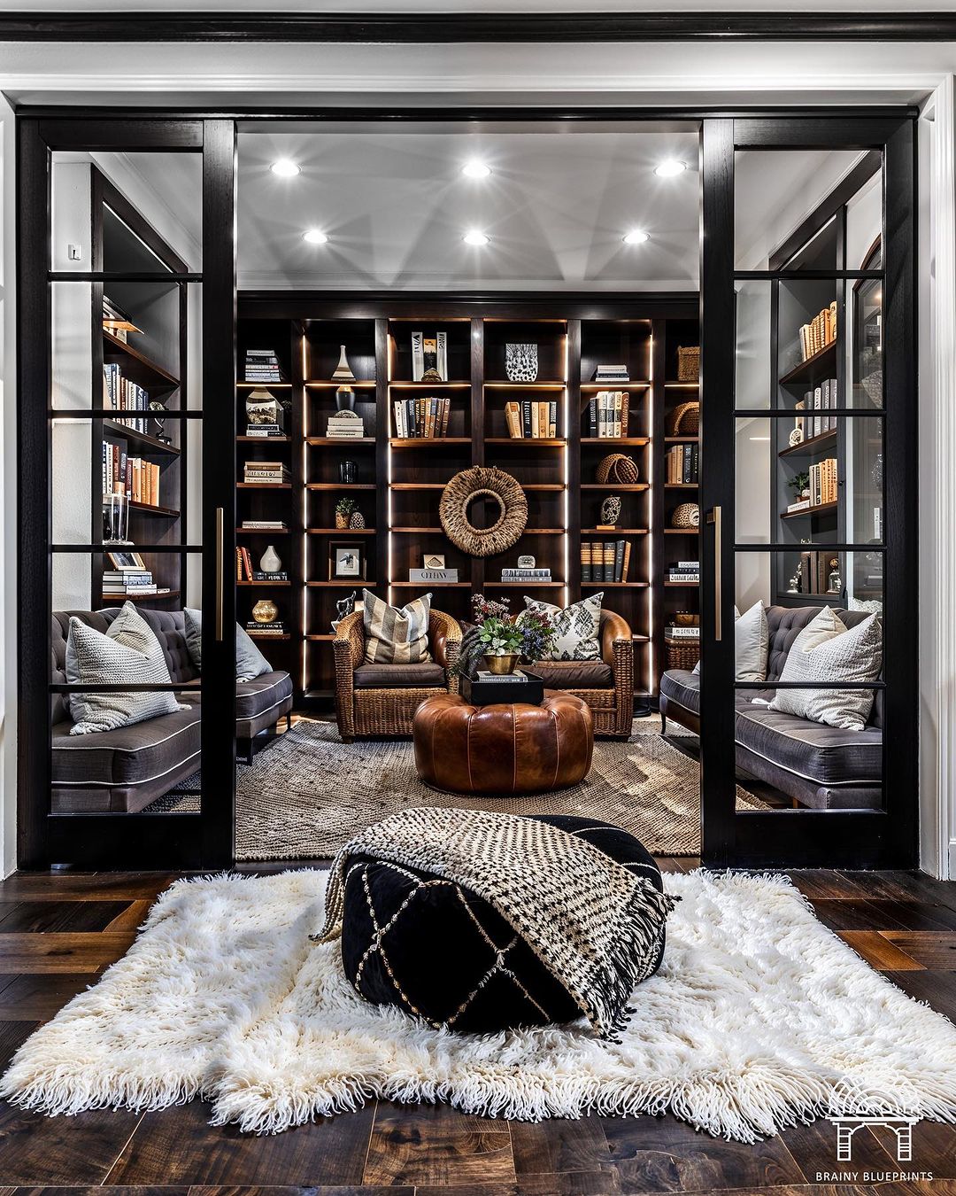 A sophisticated and welcoming home library featuring a plush rug and cozy seating framed by glass doors