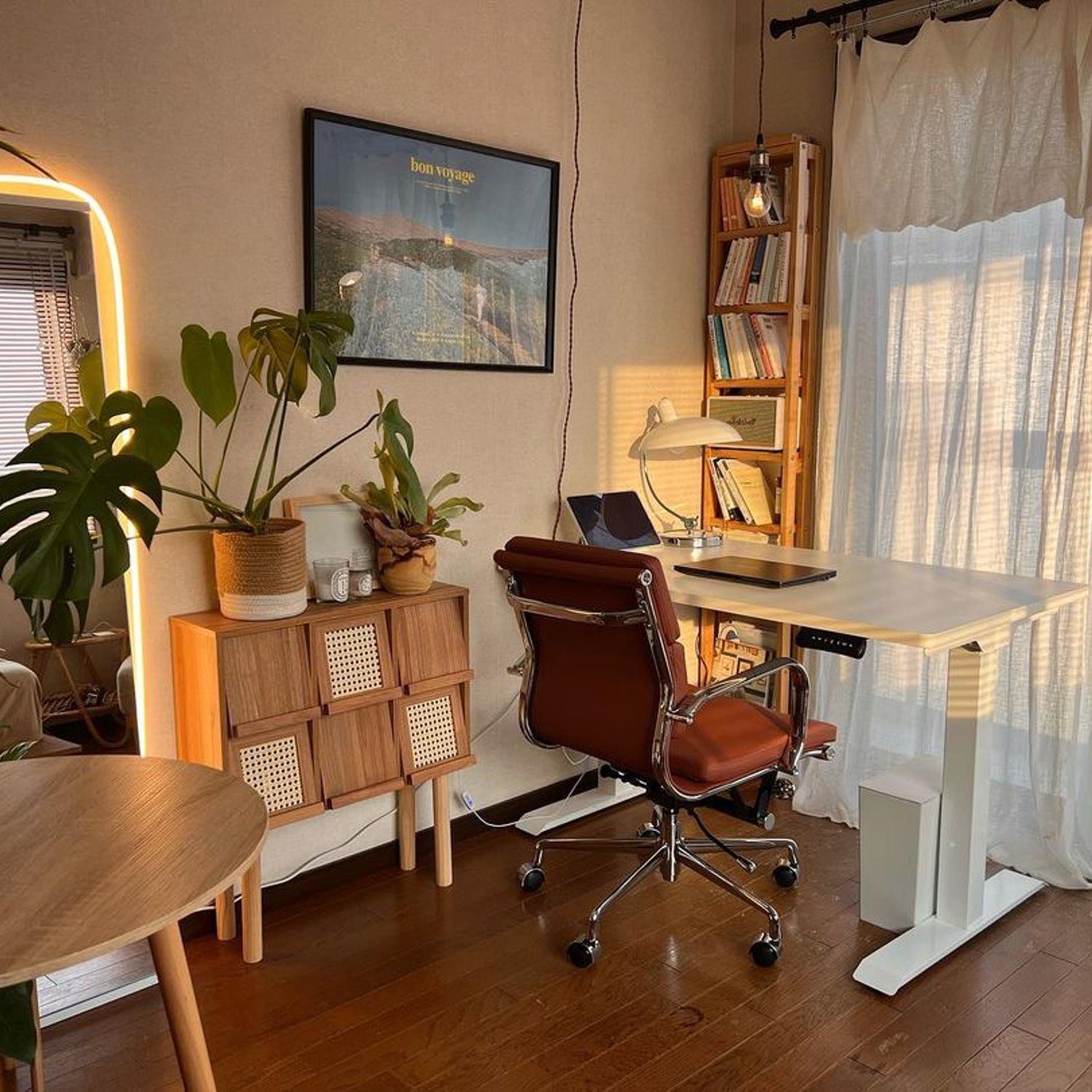 A cozy and warmly lit home office featuring a sleek adjustable standing desk, a comfortable leather chair, and surrounding wooden accents