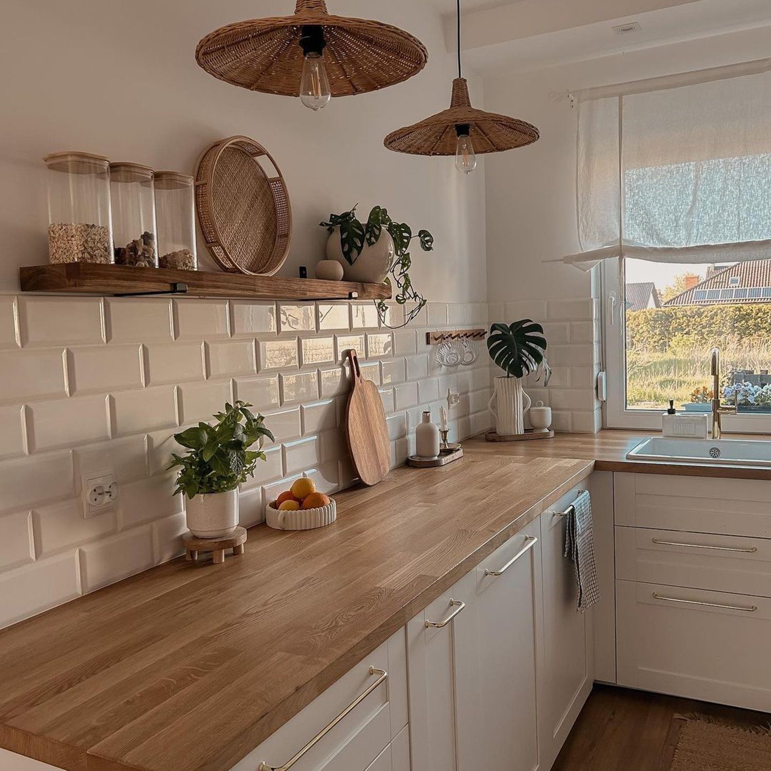 A warm and inviting kitchen space featuring wicker pendant lights, white subway tiles, and wooden countertops