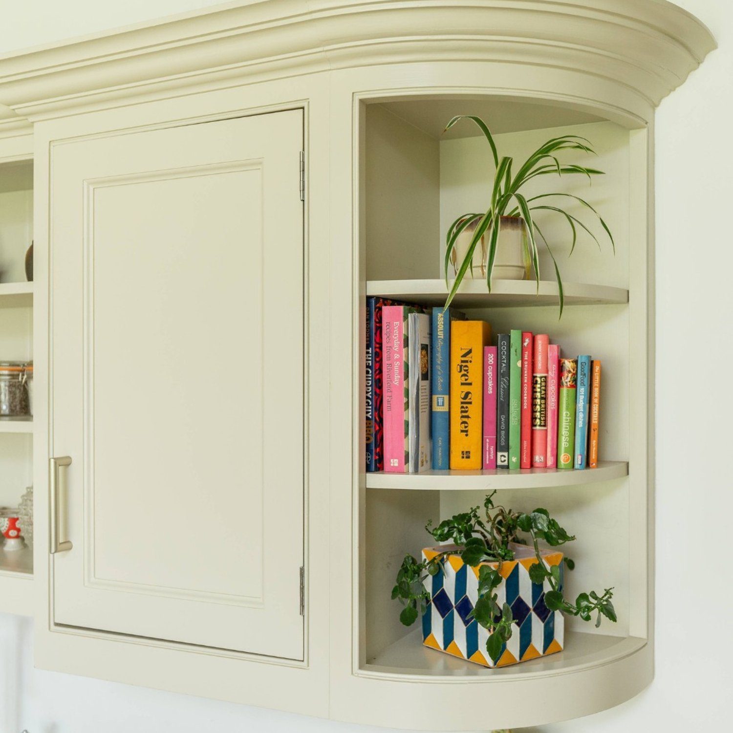 A neatly organized corner shelf in a kitchen with books and plants