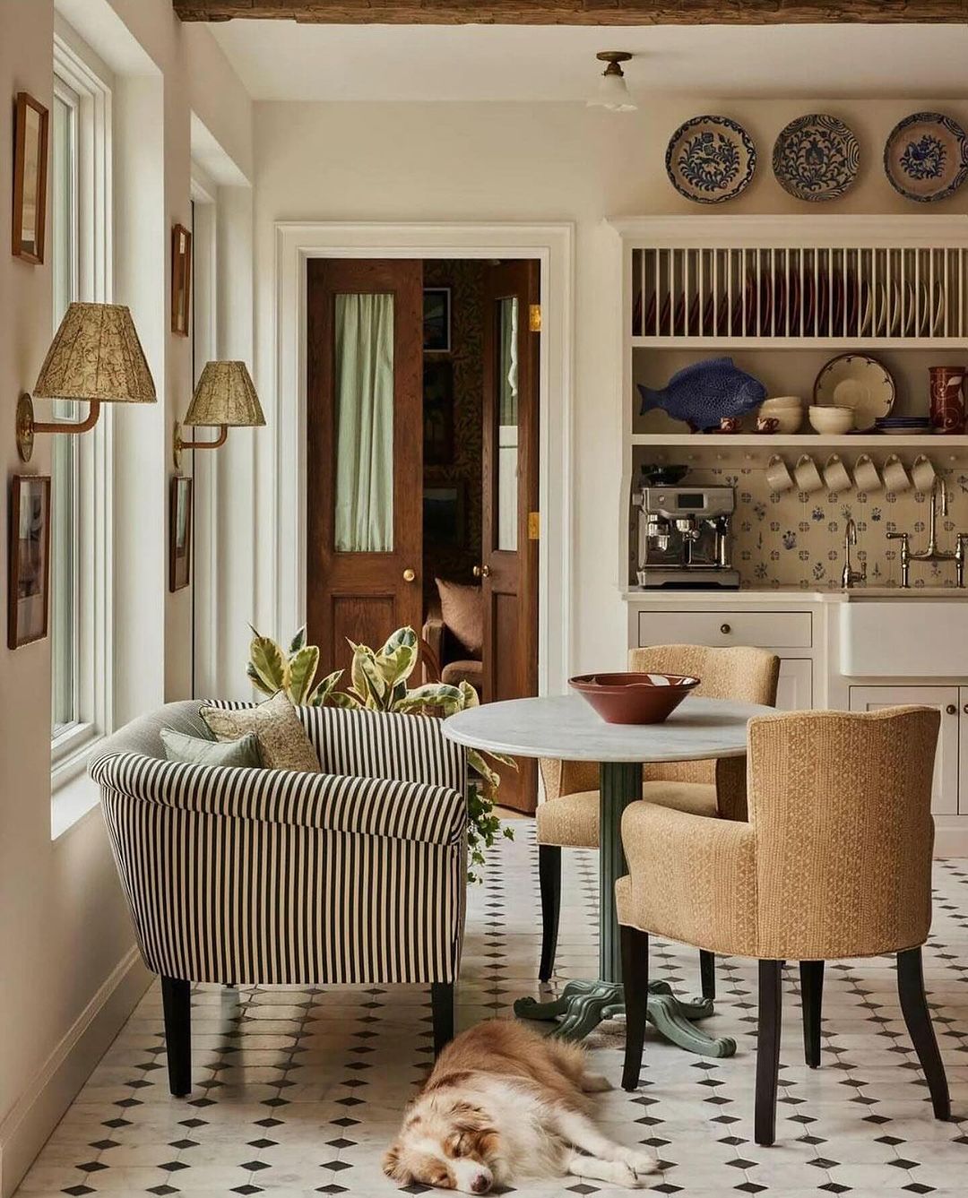 A cozy and inviting kitchen dining area with a striped banquette, classic chairs, and geometric floor tiles