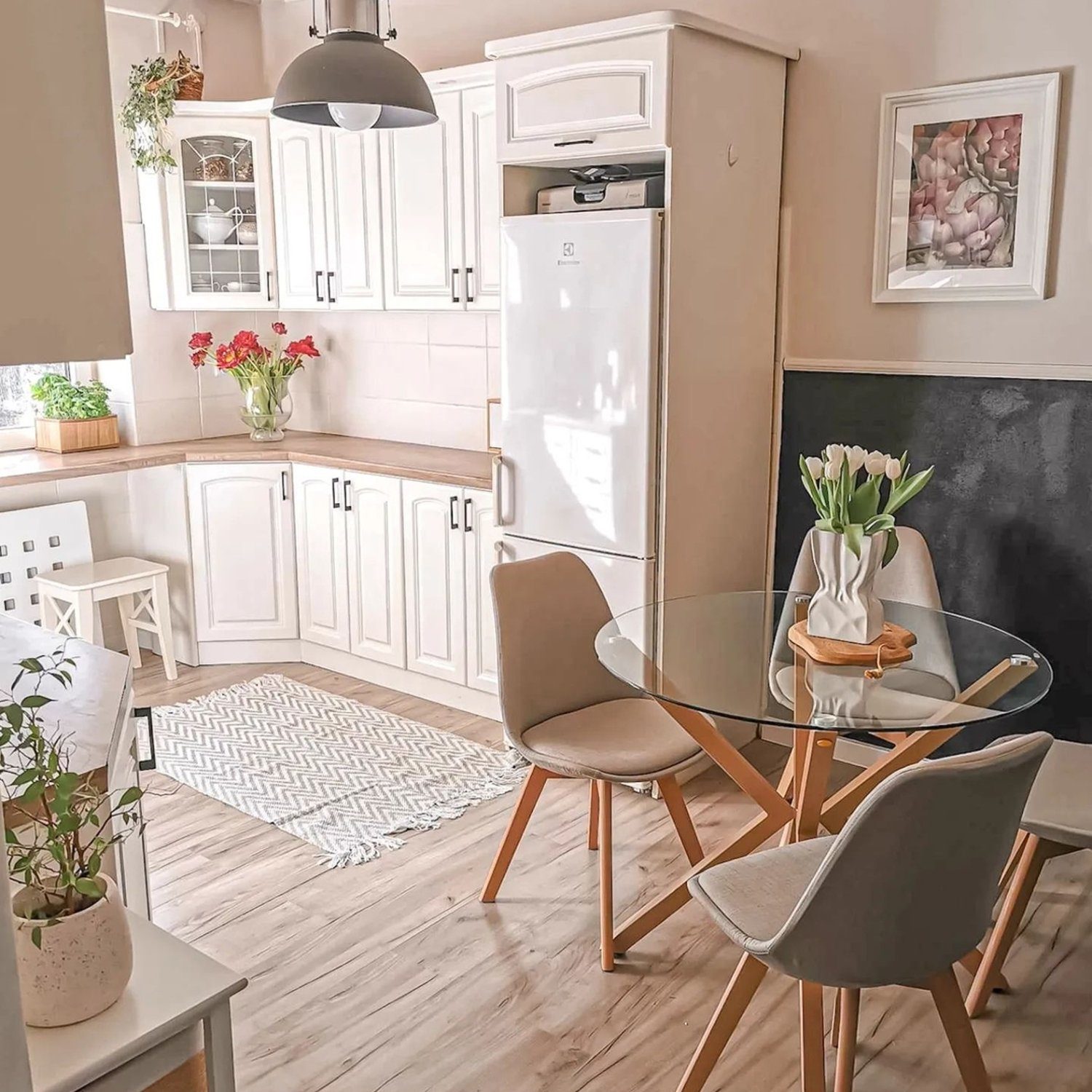 A cozy kitchen nook featuring a glass dining table and modern chairs, brightened by natural light.