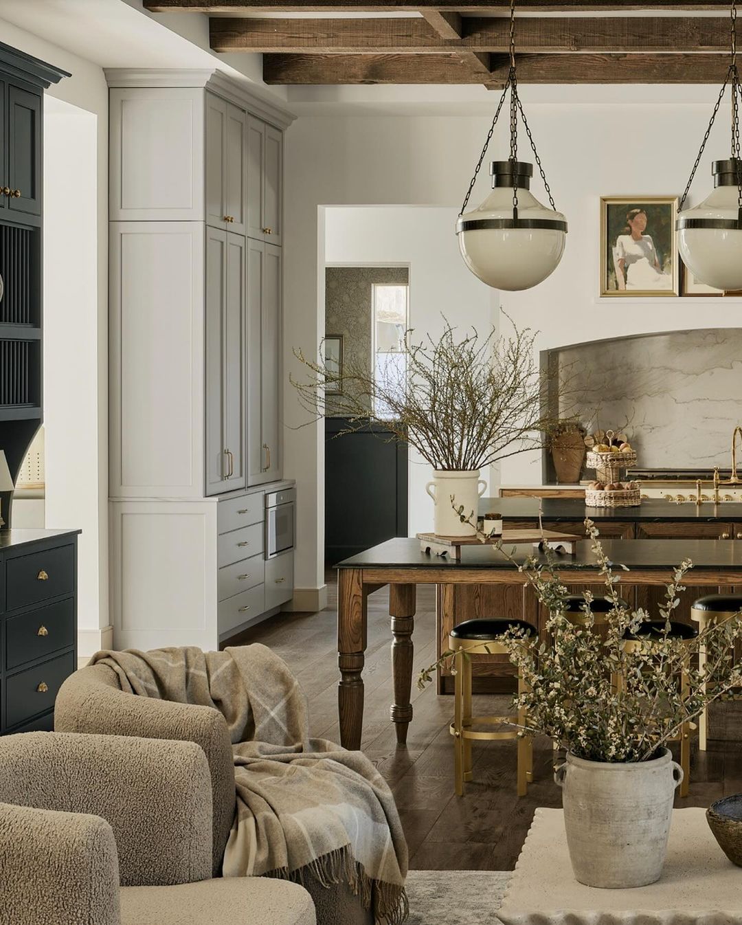 A cozy and inviting kitchen space with exposed wooden beams, marble countertops, and chic pendant lighting.