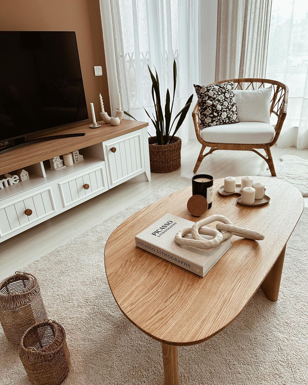 A cozy living room nook featuring a rattan armchair, a sleek TV setup, and natural accents