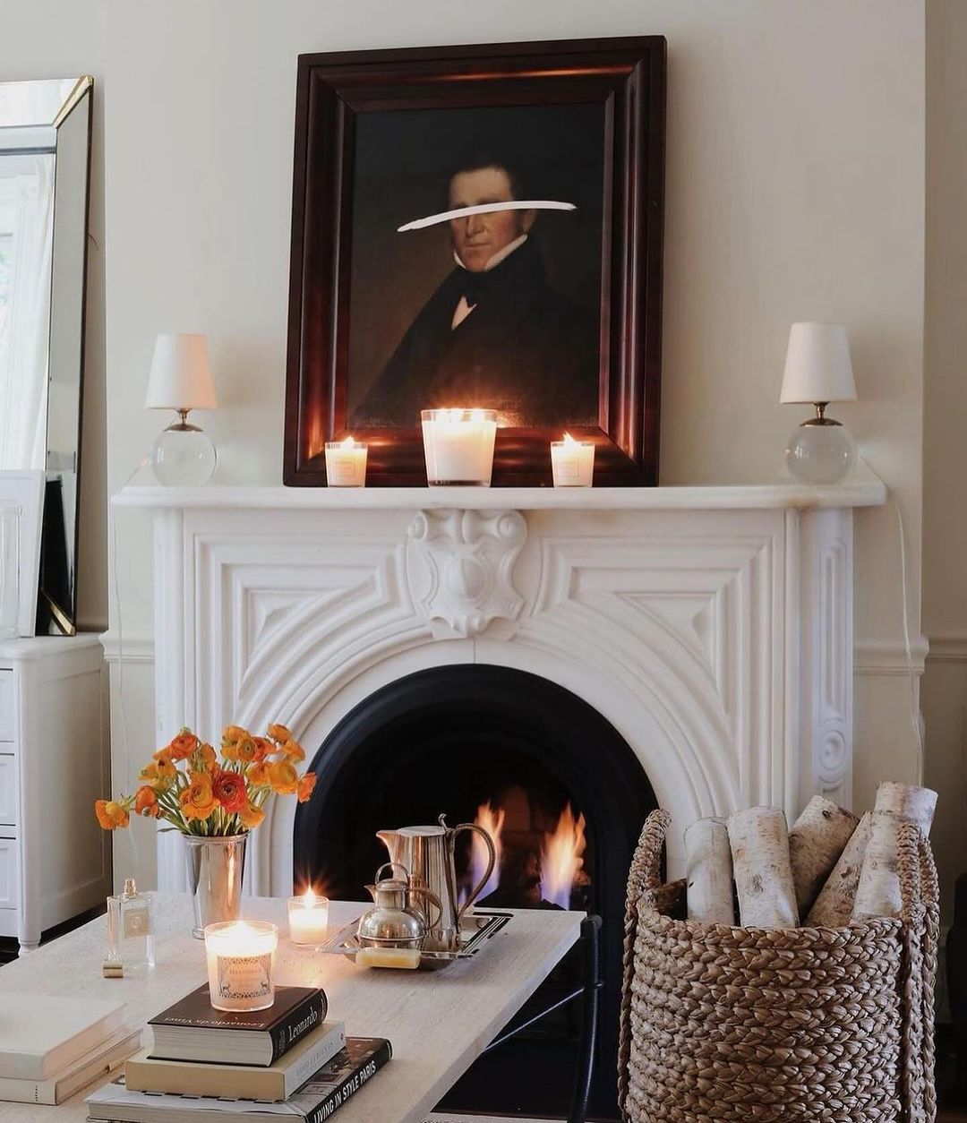 A classic fireplace with a mirror and a portrait above it creating a unique visual effect