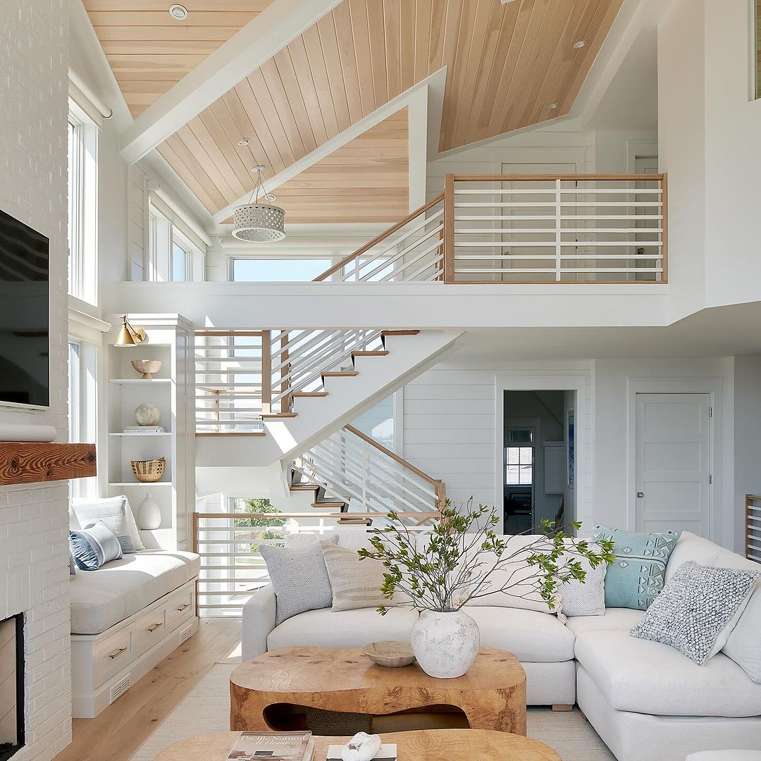 A bright and airy living room featuring high ceilings and a wooden loft area