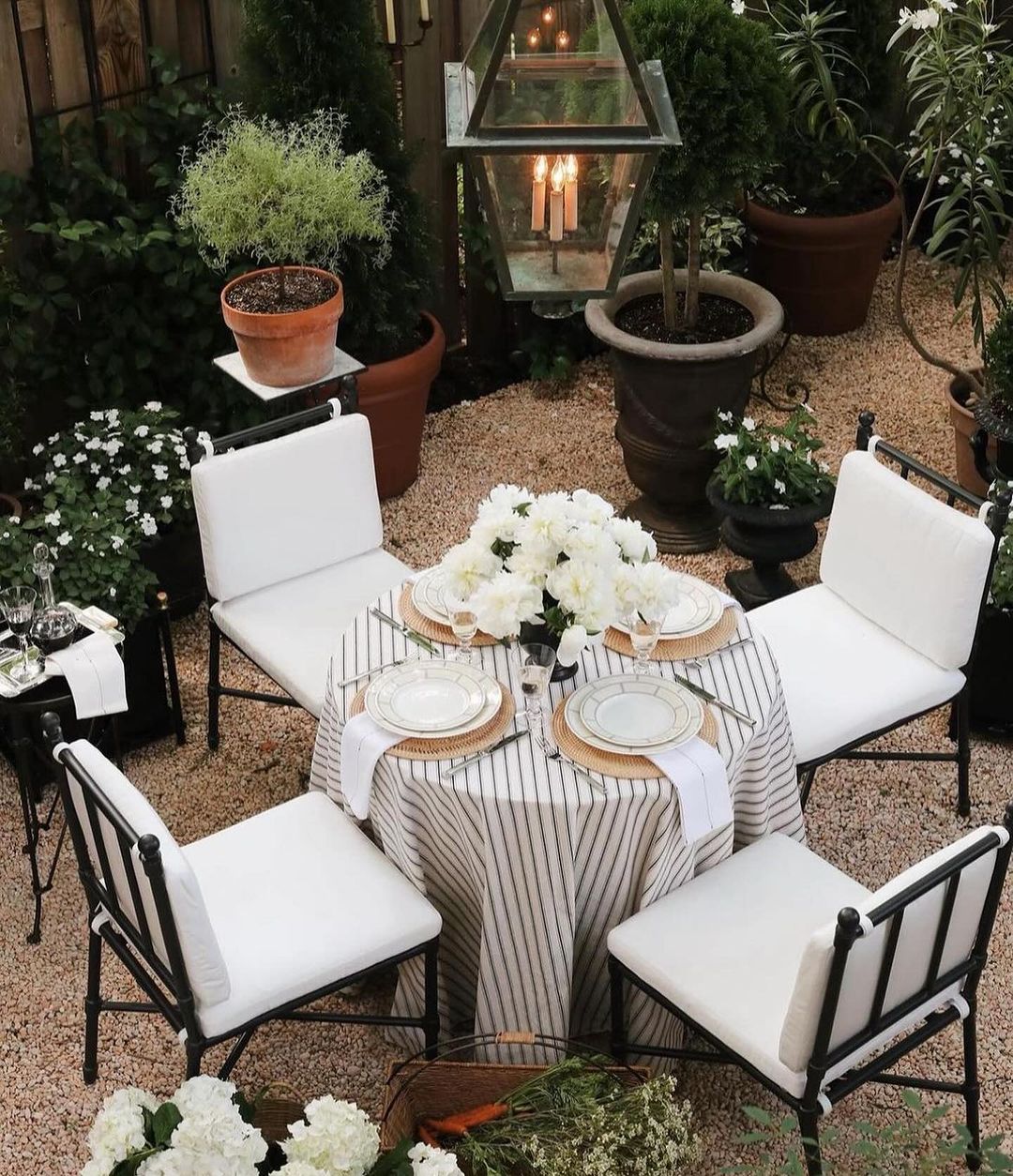 A cozy outdoor dining setup surrounded by lush green plants and soft lighting