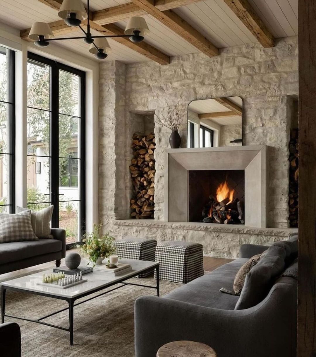 A cozy and rustic living room featuring a stone fireplace and a woodpile