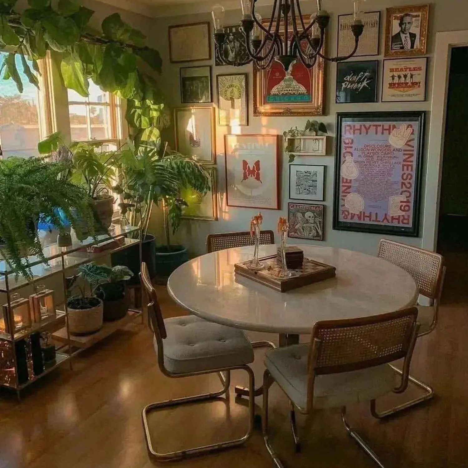 An eclectic dining room featuring a variety of indoor plants, wall art, and a round marble table.