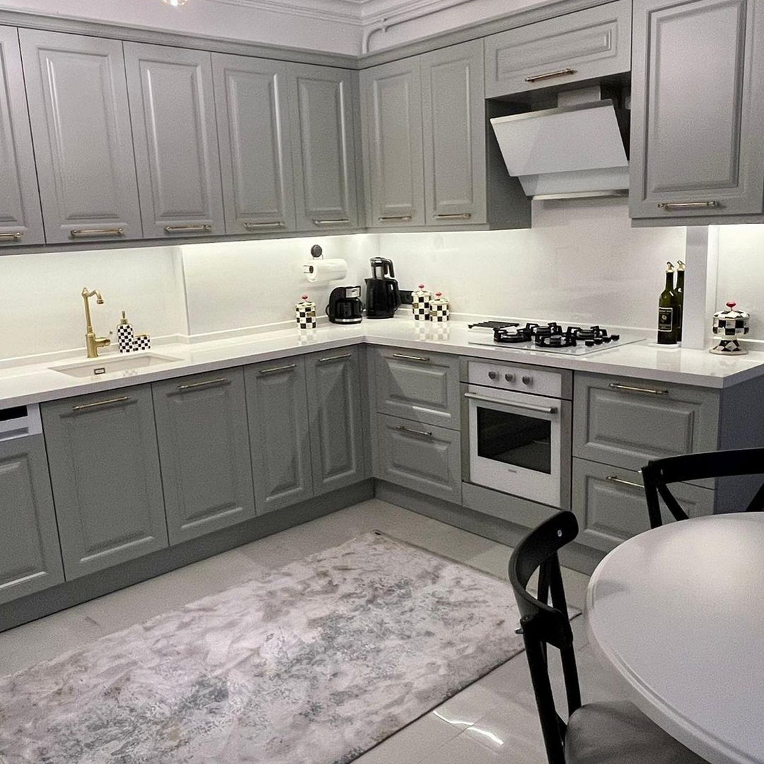 A modern and neatly organized kitchen with grey cabinets and white countertops