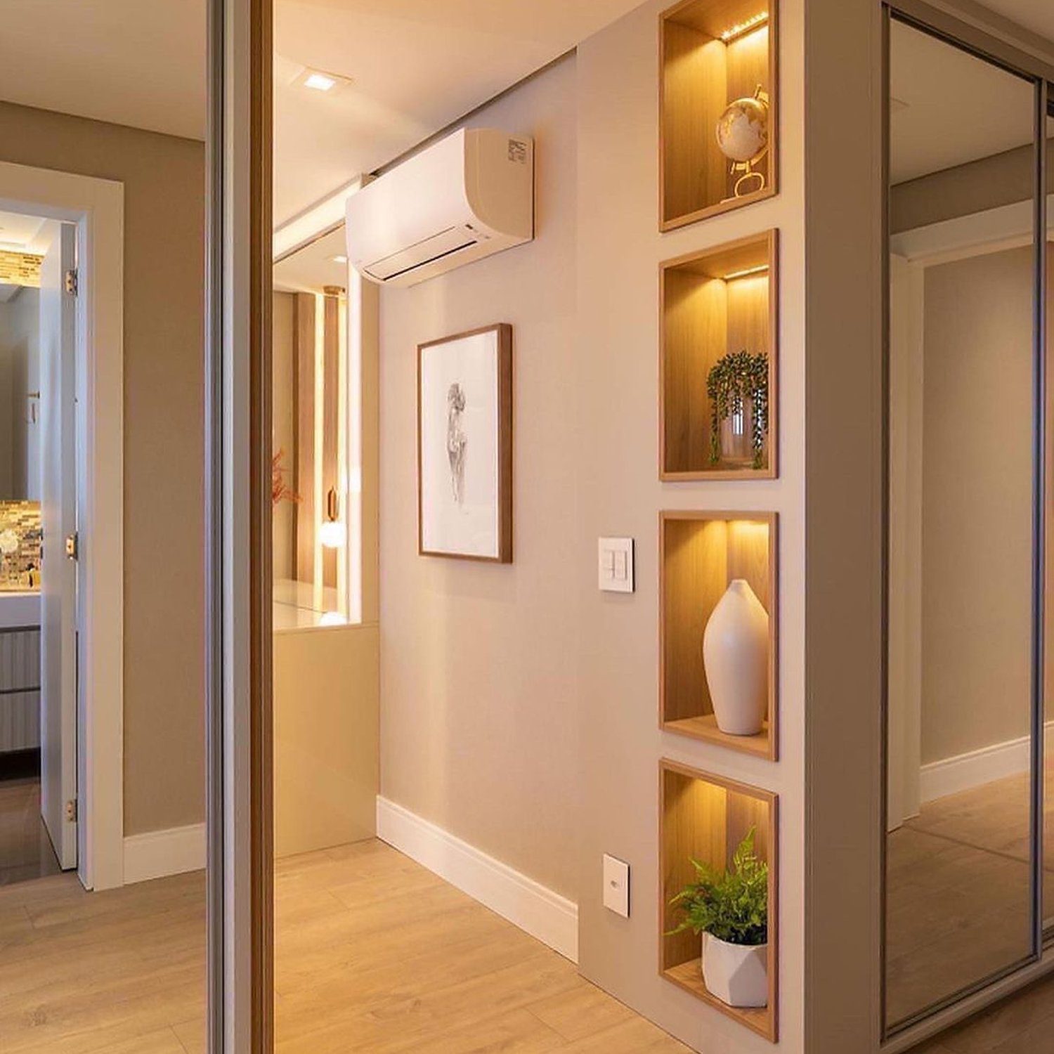 An elegantly designed hallway featuring recessed lighting, warm wooden floors, and a built-in display niche with accent lights