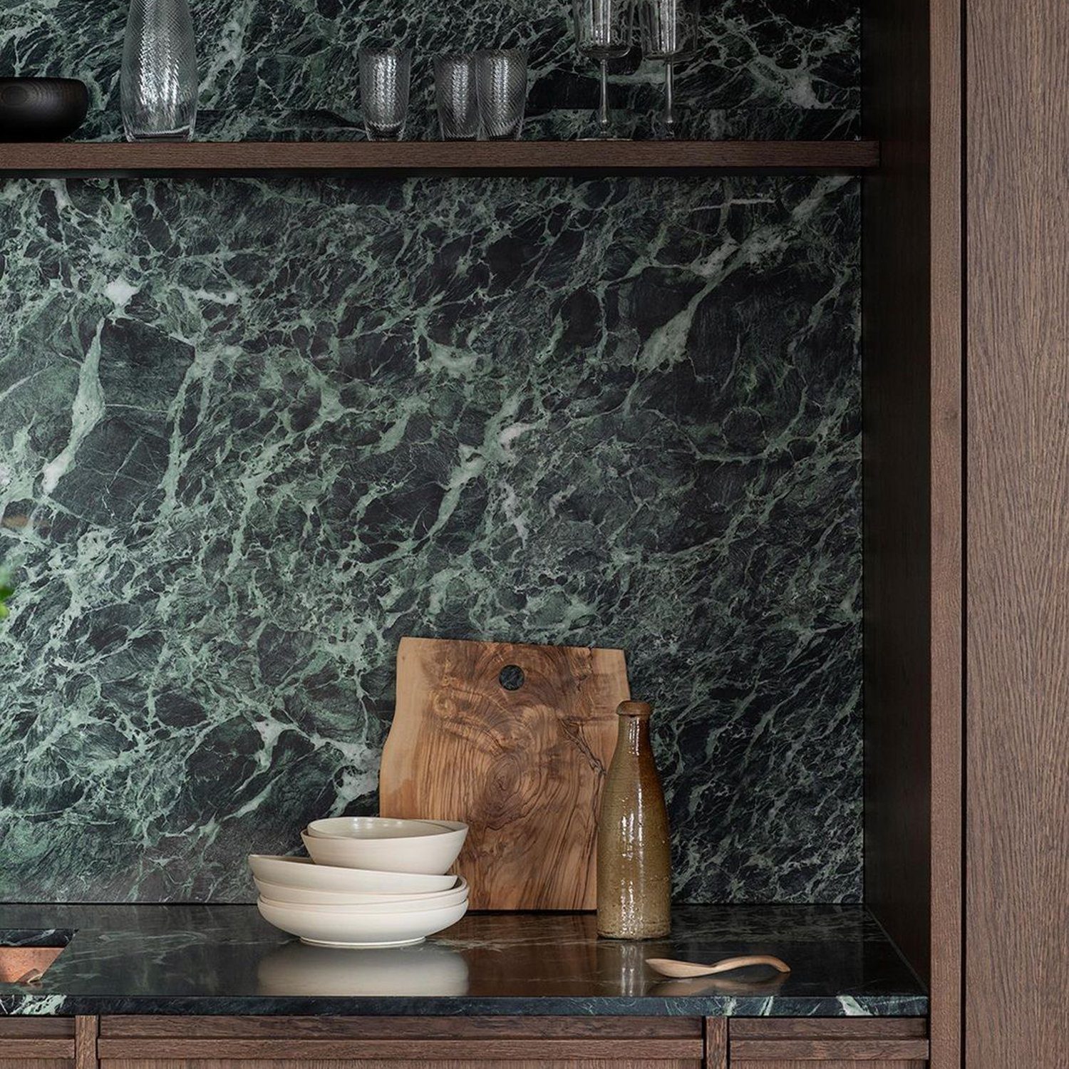 Elegant kitchen corner with a backsplash in variegated dark green marble, giving a luxurious and natural touch.