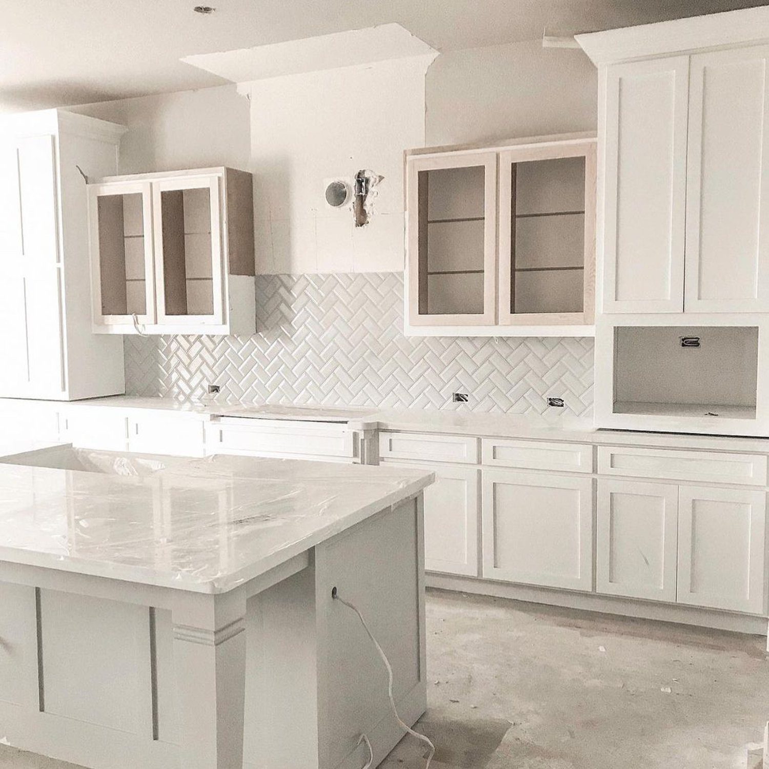 Under construction kitchen with herringbone backsplash and white cabinets