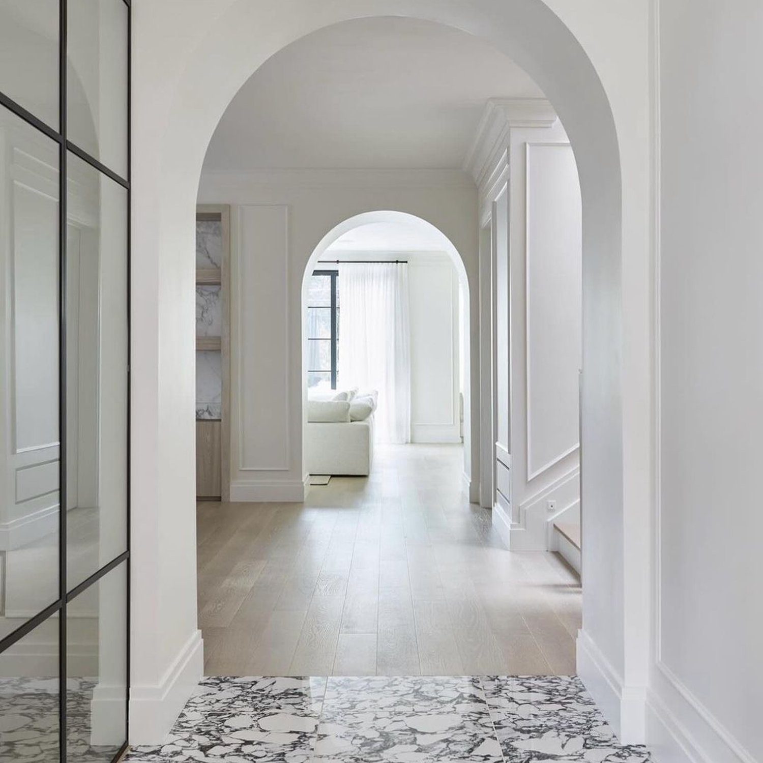 Elegant minimalist corridor design featuring marble and hardwood flooring.