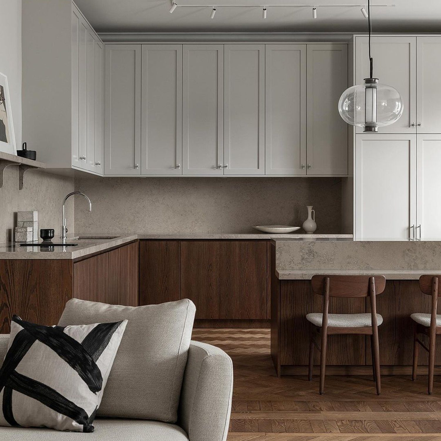 A modern and stylish kitchen with seamless cabinetry and herringbone wood floor.