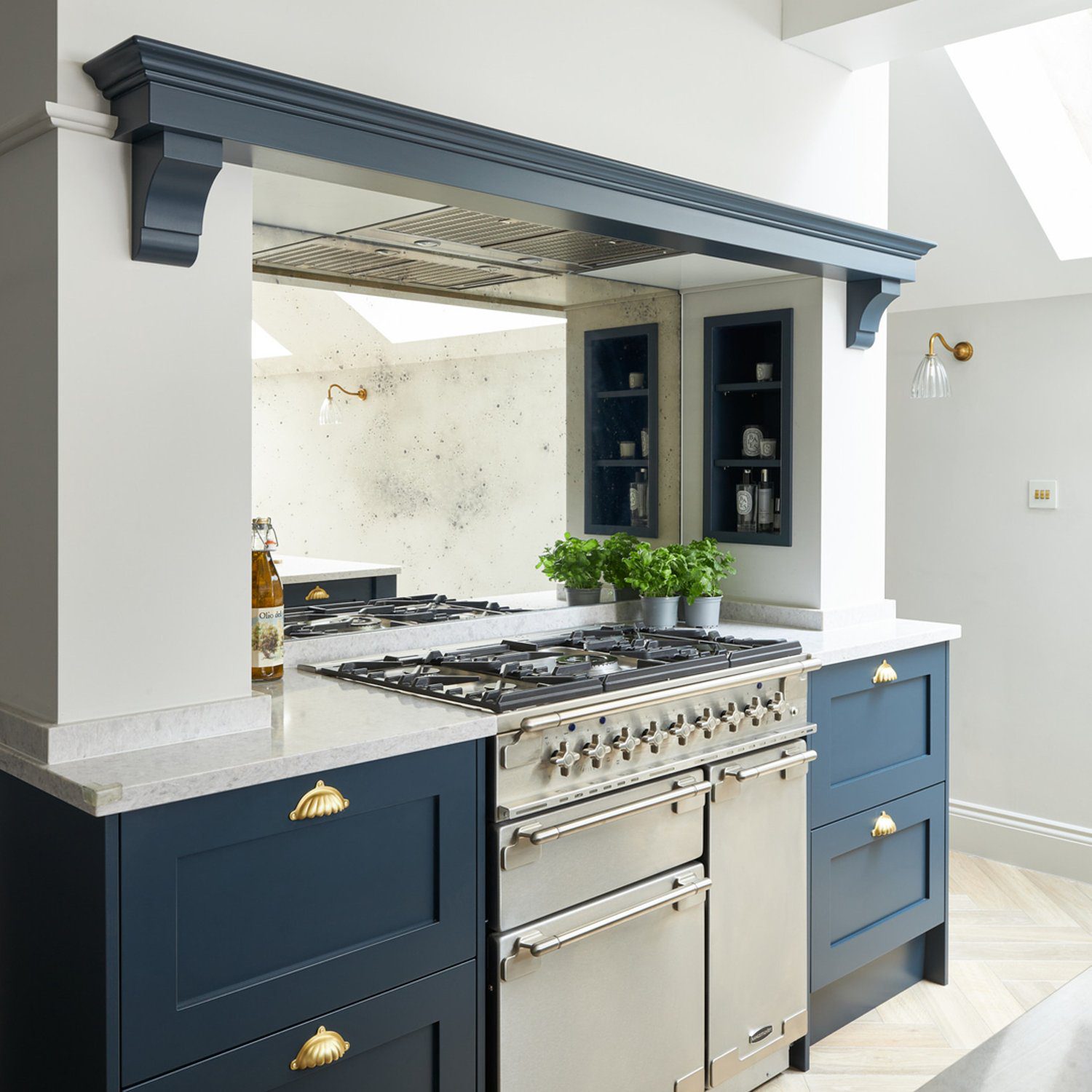 Elegant kitchen showcasing a navy blue cabinetry with brass hardware, a professional stainless steel range, and a marble backsplash