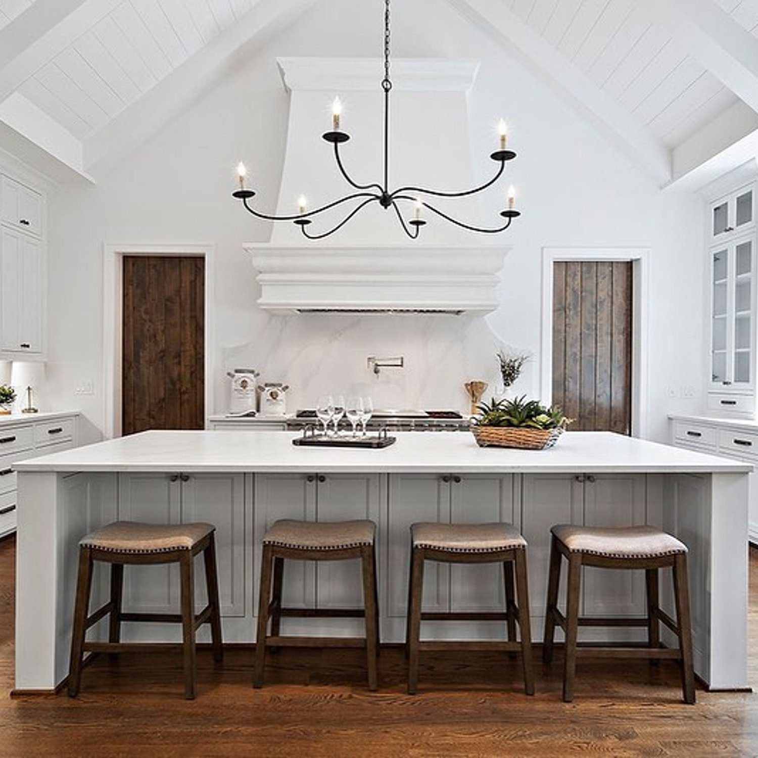 Elegant white kitchen with wooden accents featuring high vaulted ceilings