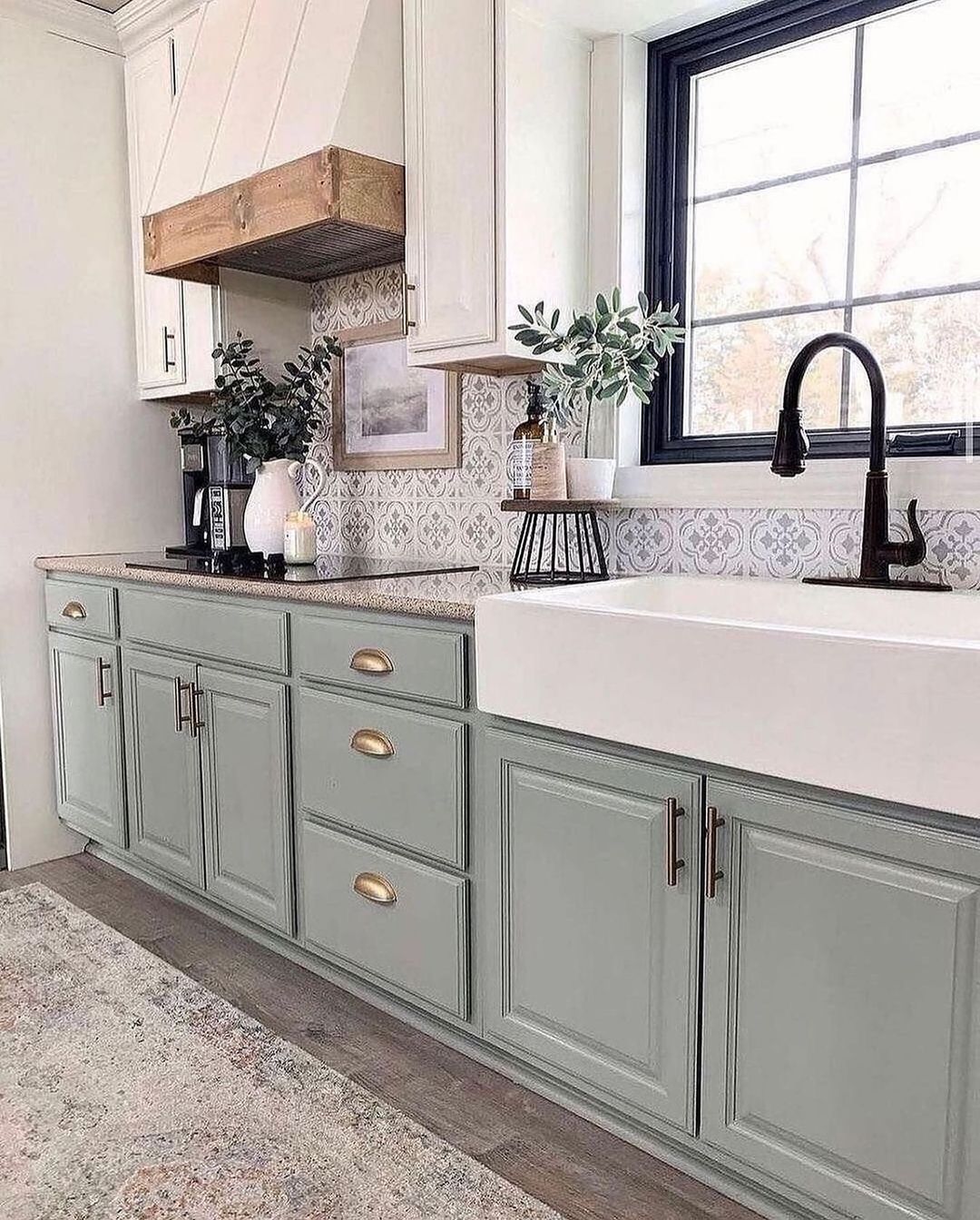 A stylish farmhouse-inspired kitchen featuring sage green cabinets and patterned backsplash